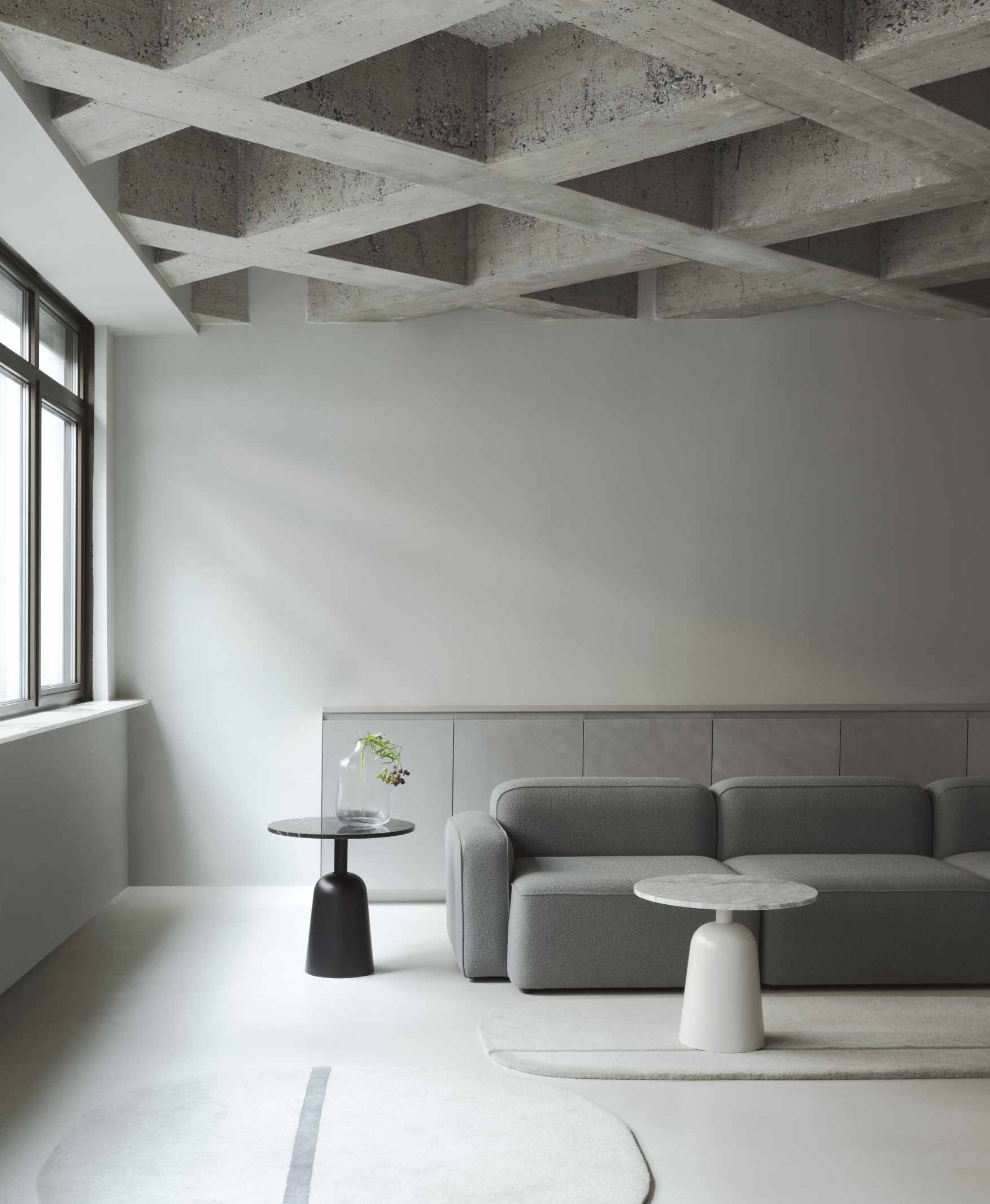 Minimalistisches Wohnzimmer mit grauem Sofa und zwei Beistelltischen, darunter ein Turn Table Marmor Tisch von Normann Copenhagen.