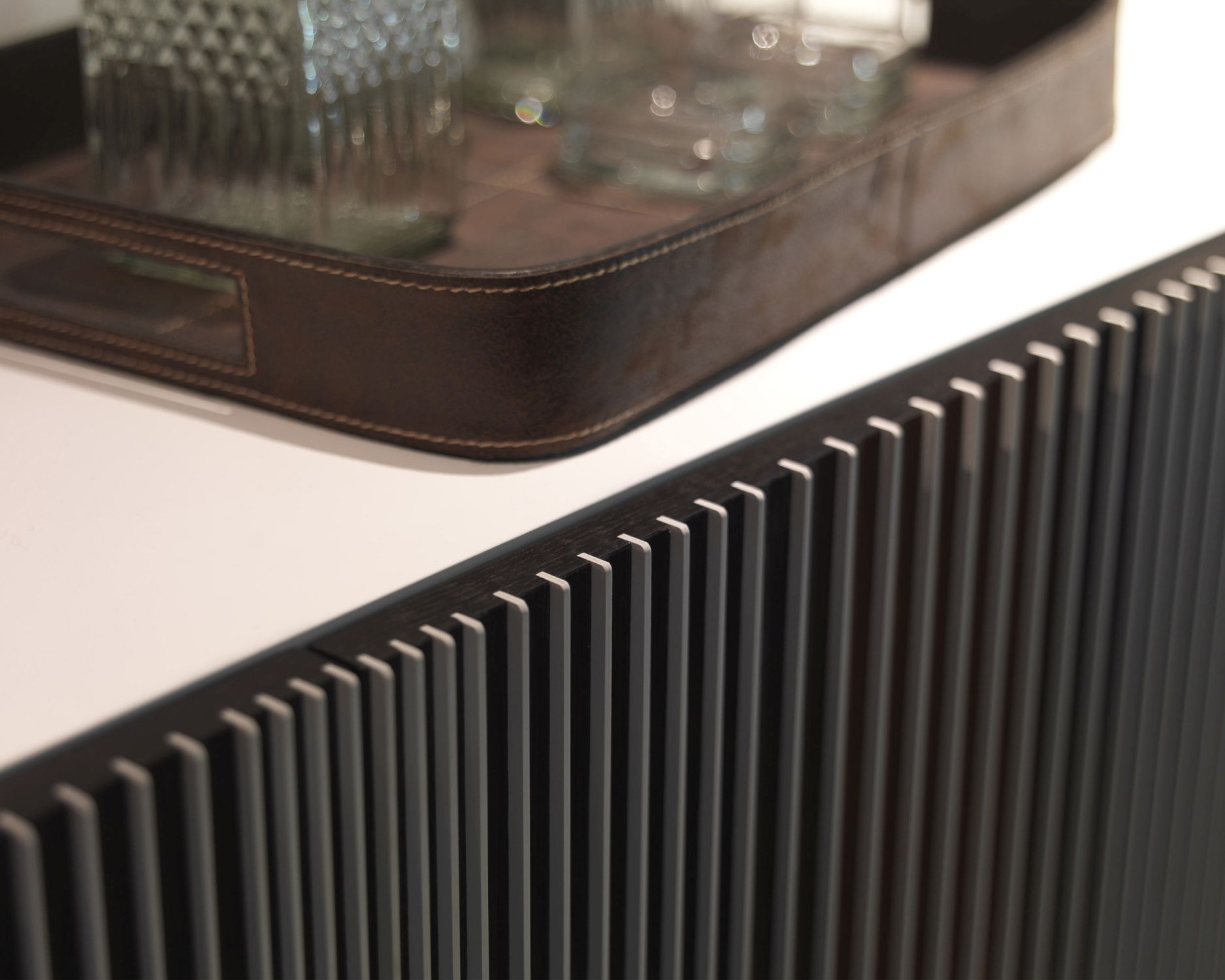 Detailaufnahme der Carlos Anrichte mit geriffelter Front und Leder-Tablett mit Gläsern.