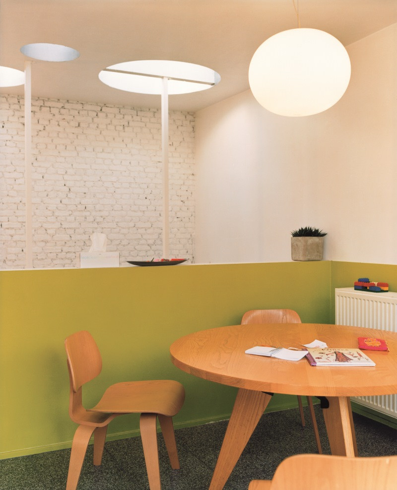 Nahaufnahme eines Vitra Plywood Group DCW Holzstuhls in einem modern eingerichteten Raum.