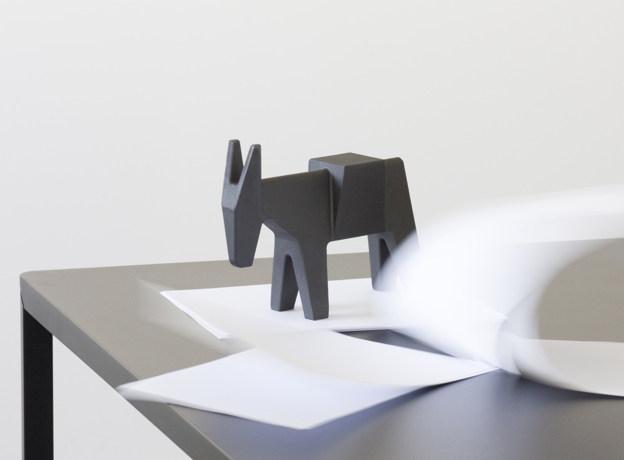 Schwarzer Ettore Türstopper in Eselform von Magis auf einem Tisch mit Papier. Design Türstopper.