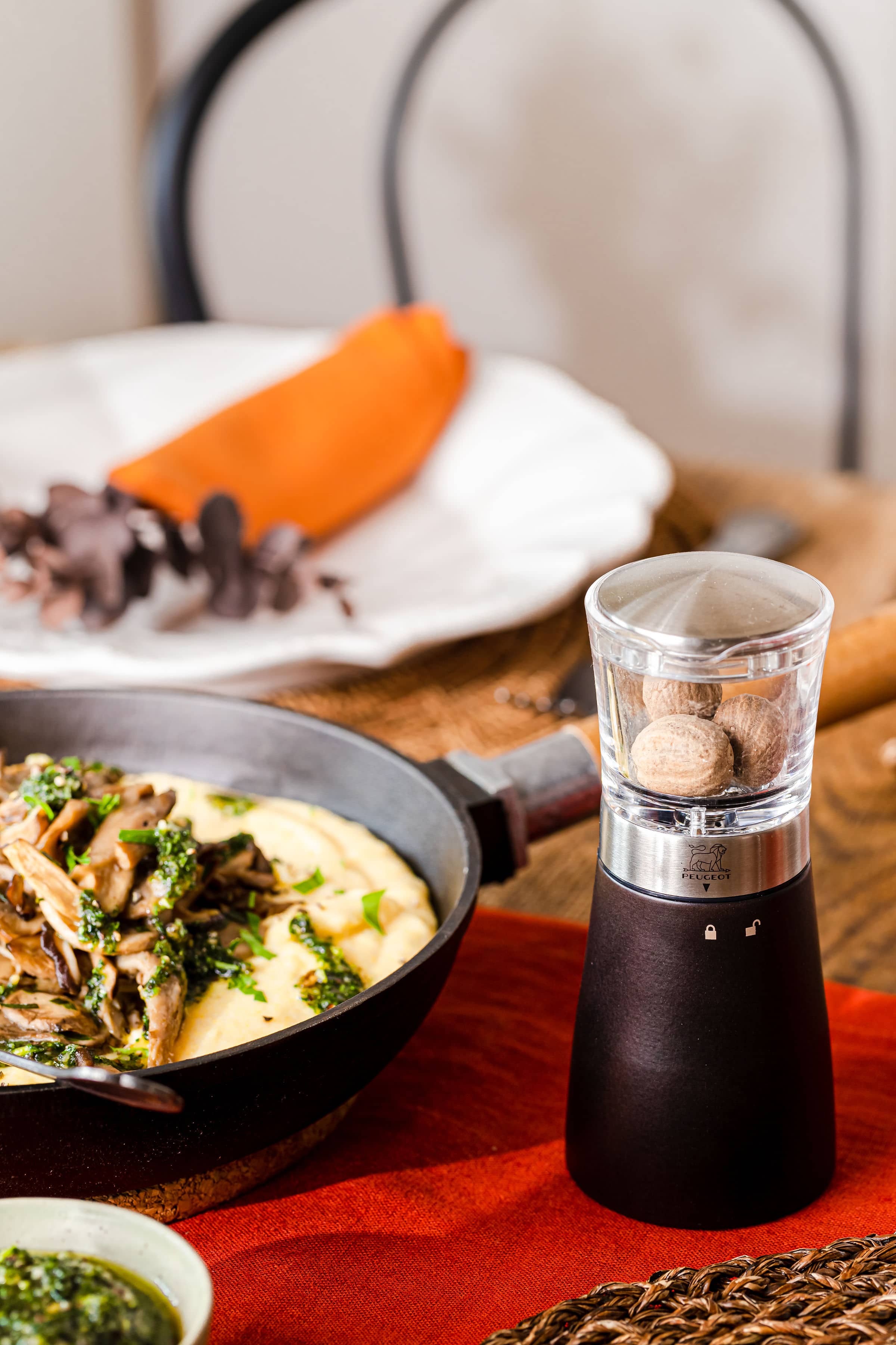 Nahaufnahme der Peugeot Muskatmühle Daman neben einem Gericht mit Pilzen und Polenta.