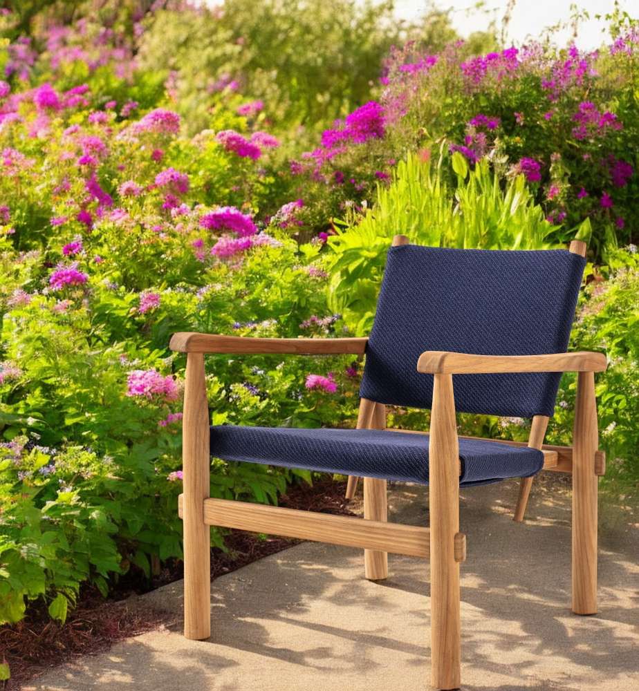 Doron Sessel Outdoor: Blauer Gartensessel aus Holz von Cassina vor blühendem Garten.