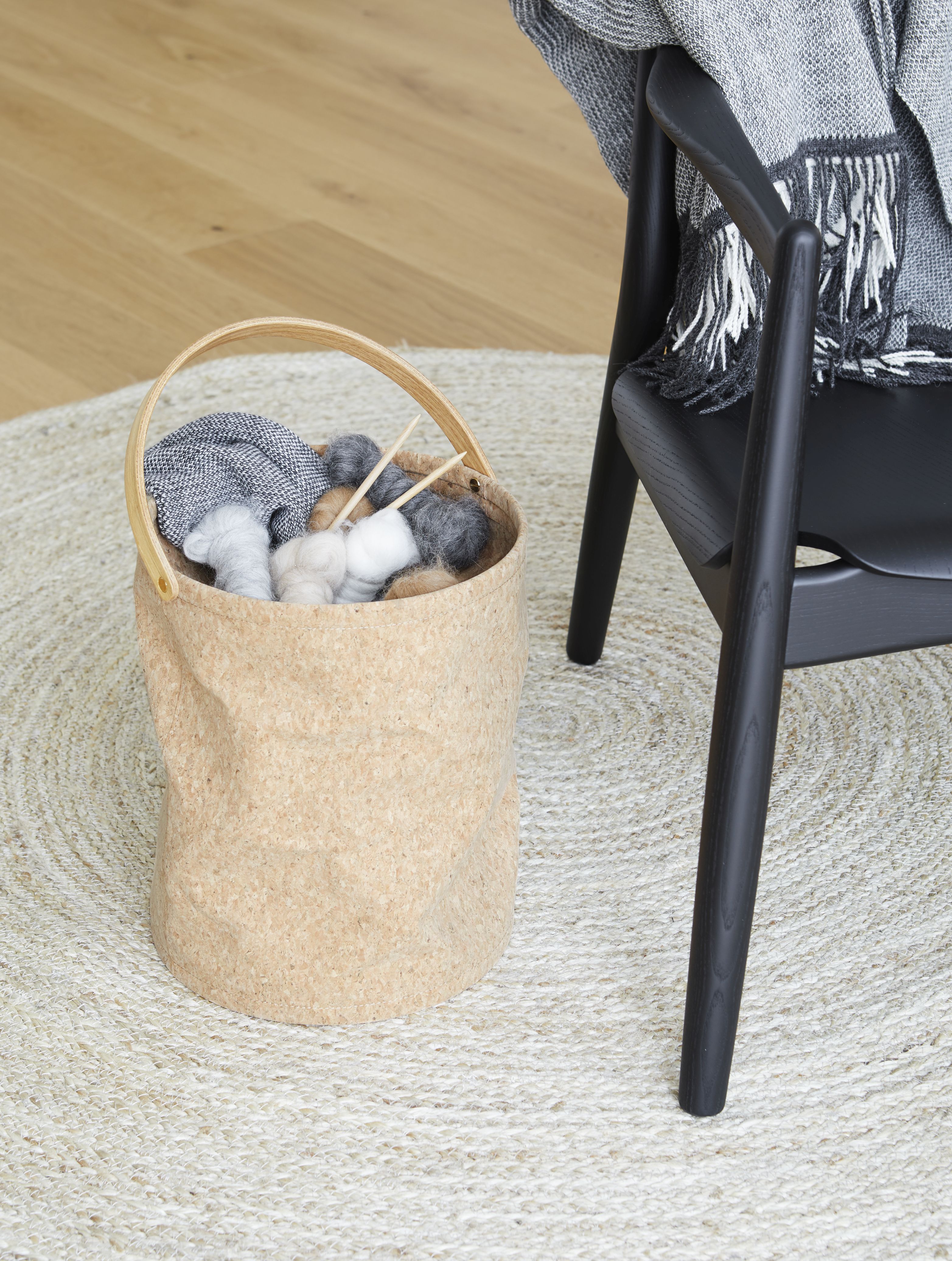 Aymara Decke in Korb neben Stuhl auf Teppich. Gemütliches Wohnambiente mit Textilien.