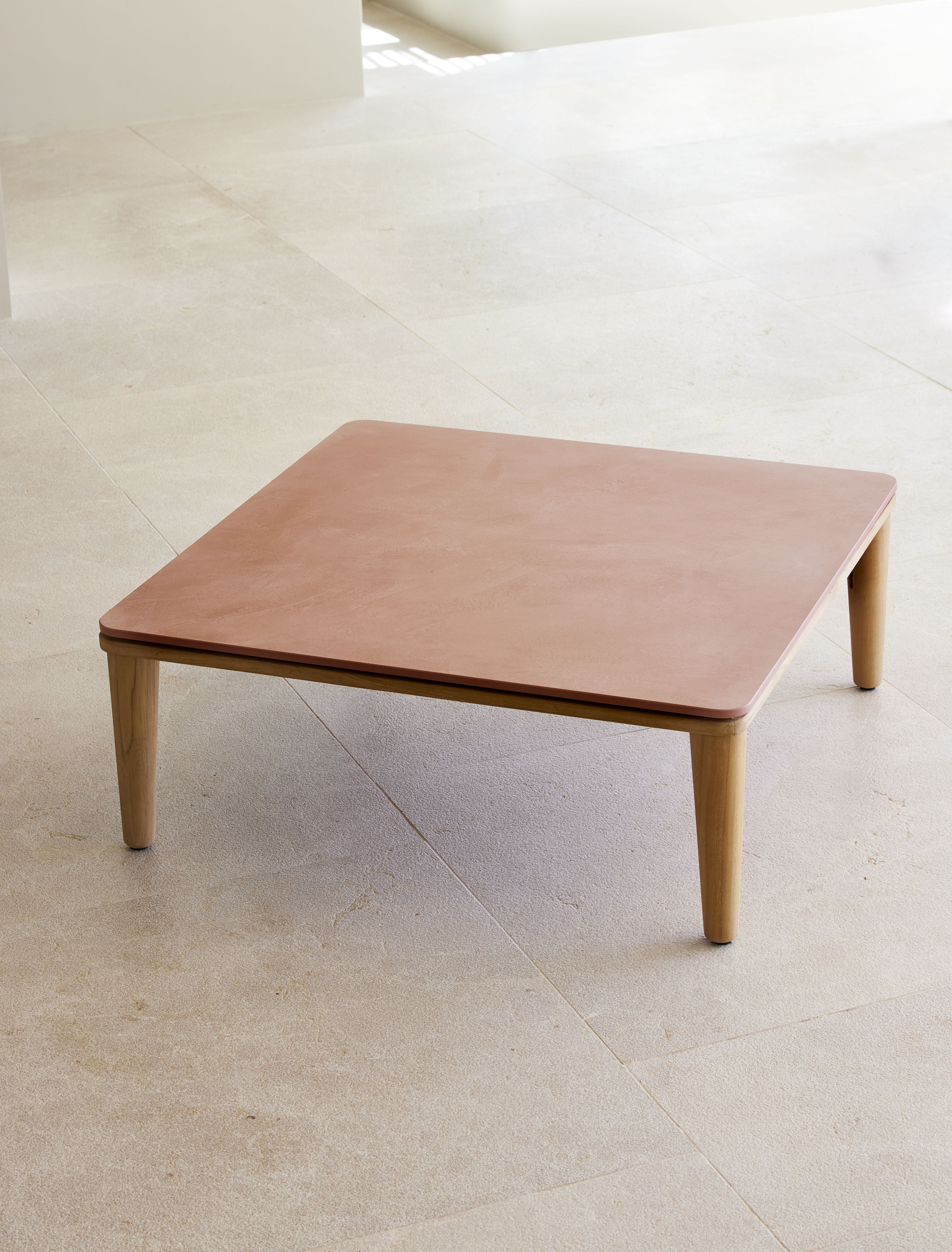 Quadratischer Cane-Line Capture Outdoor Couchtisch mit rosa Tischplatte und Holzbeinen.