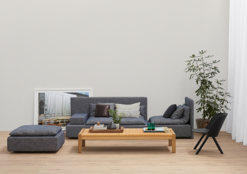 Wohnzimmer mit grauem EC05 That Sessel, passendem Hocker und Holztisch von e15.