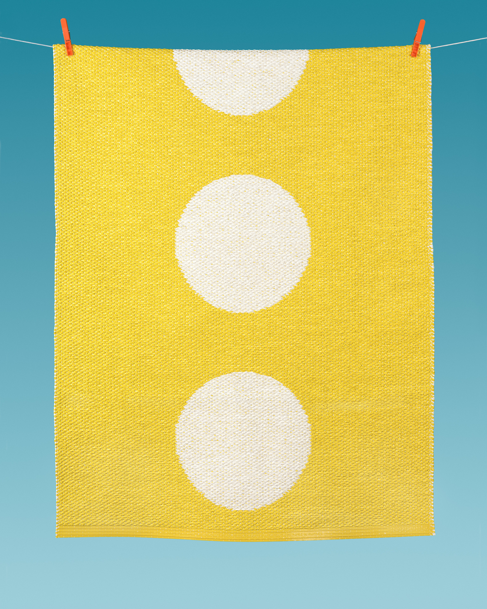 Vera Kunststoffteppich gelb mit weißen Punkten hängt an einer Wäscheleine, ideal für Küche und Bad.