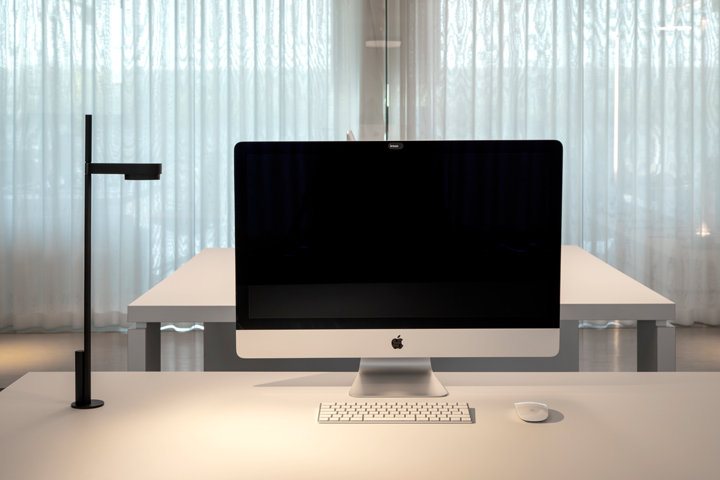 Kido Desk Tischaufbauleuchte von Belux am Schreibtisch mit Computer und Zubehör.