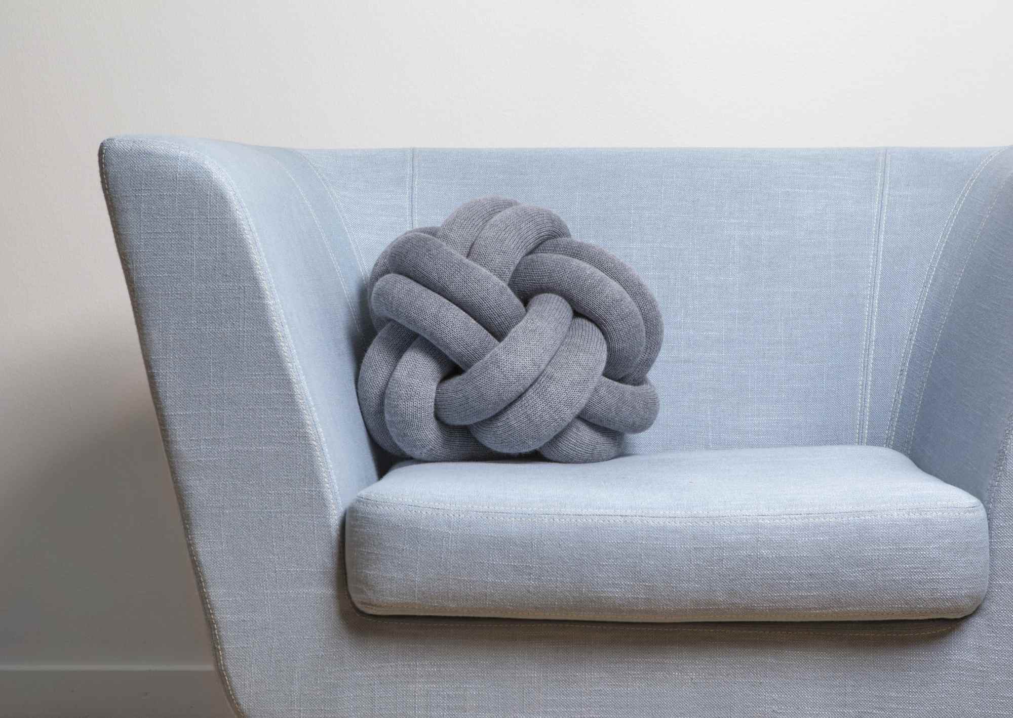 Graues Knot Kissen von Design House Stockholm auf einem hellblauen Sessel. Dekokissen und Wohnaccessoires.