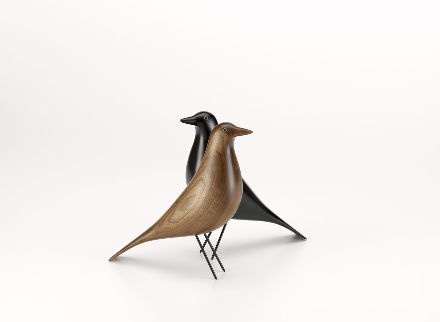 Zwei Eames House Bird Skulpturen von Vitra, eine aus Nussbaum, eine schwarz. Dekorative Designobjekte.