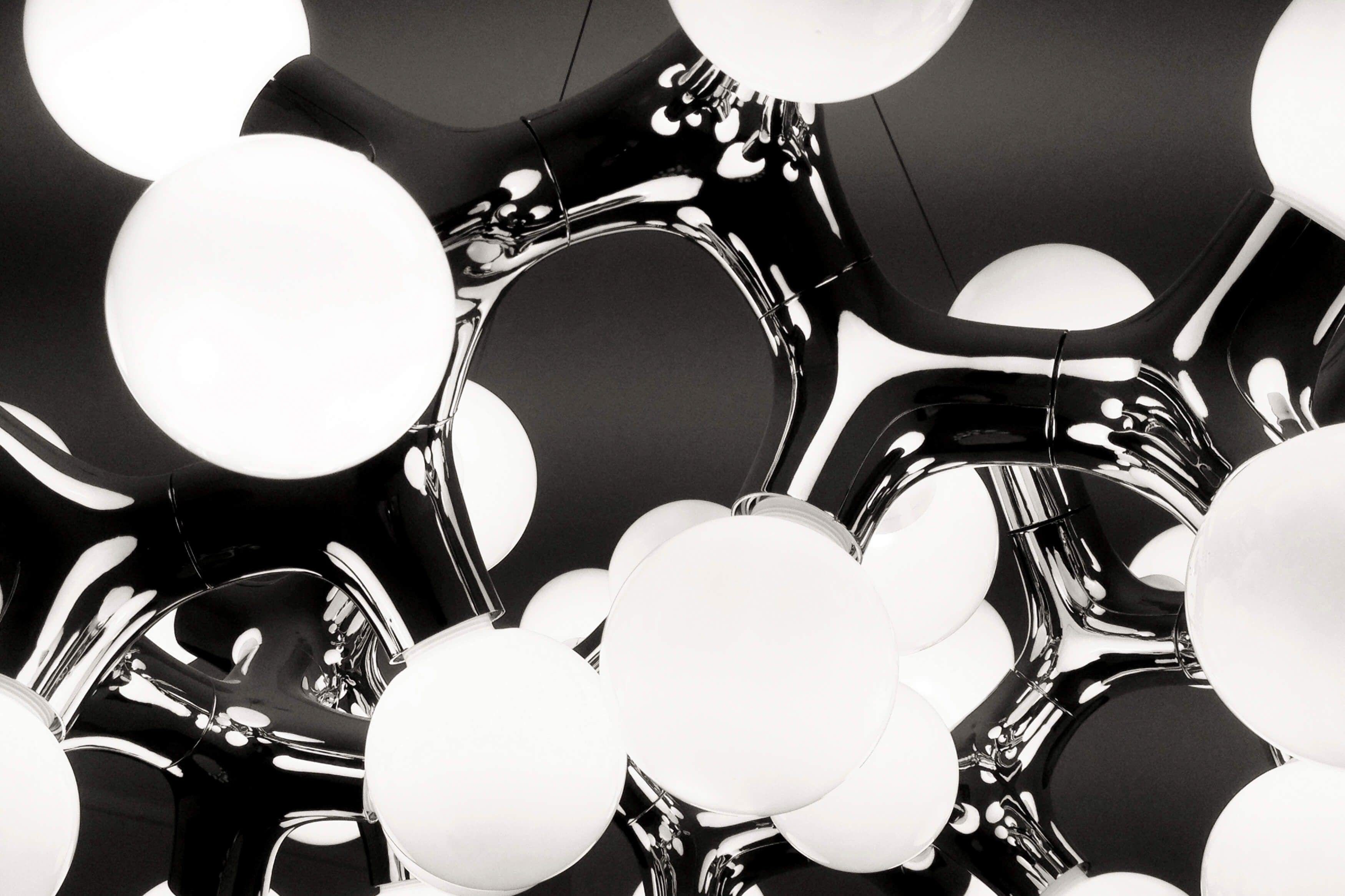 Detailaufnahme der DNA Pendelleuchte in Schwarz mit runden, weißen Lampenschirmen. Moderne Deckenleuchte für Wohnräume.