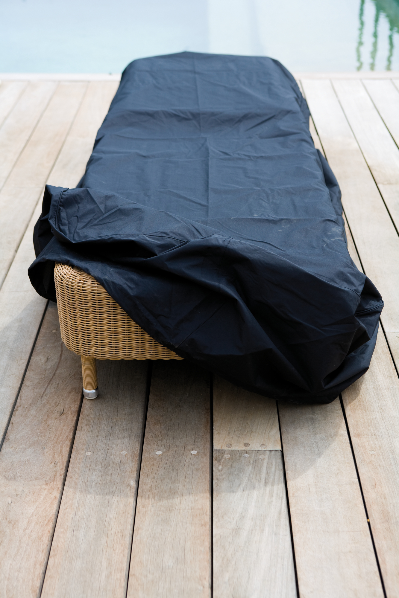 Schwarze Cane-Line Schutzhülle für große Outdoor Sofa Möbel aus Rattan auf Holzterrasse.