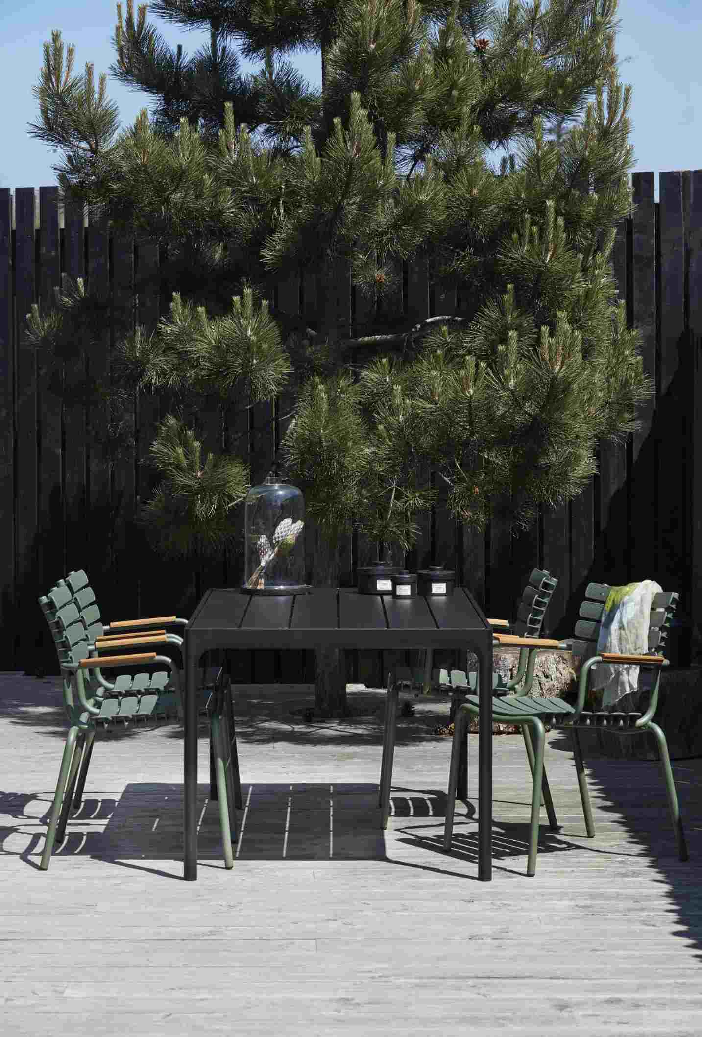 Schwarzer Houe Esstisch "Four" mit grünen Gartenstühlen auf einer Holzterrasse im Freien.