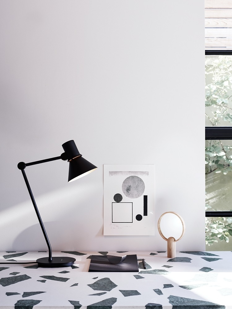 Schwarze Anglepoise Type 80 Tischleuchte auf einem Schreibtisch mit abstraktem Muster und minimalistischer Dekoration.