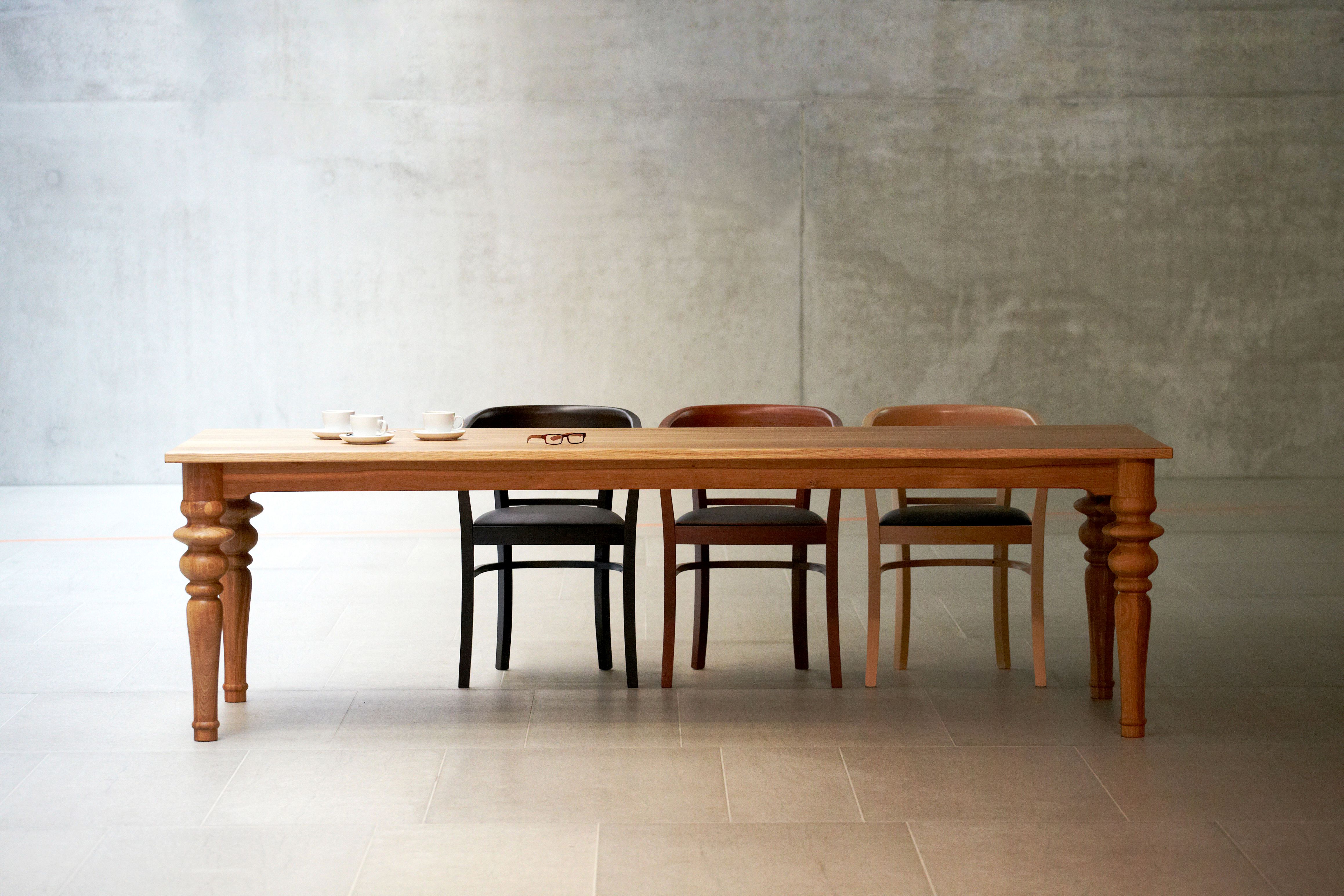 Drexler Tisch von Jan Kurtz aus Holz mit Stühlen und Kaffeetassen im minimalistischen Raum.