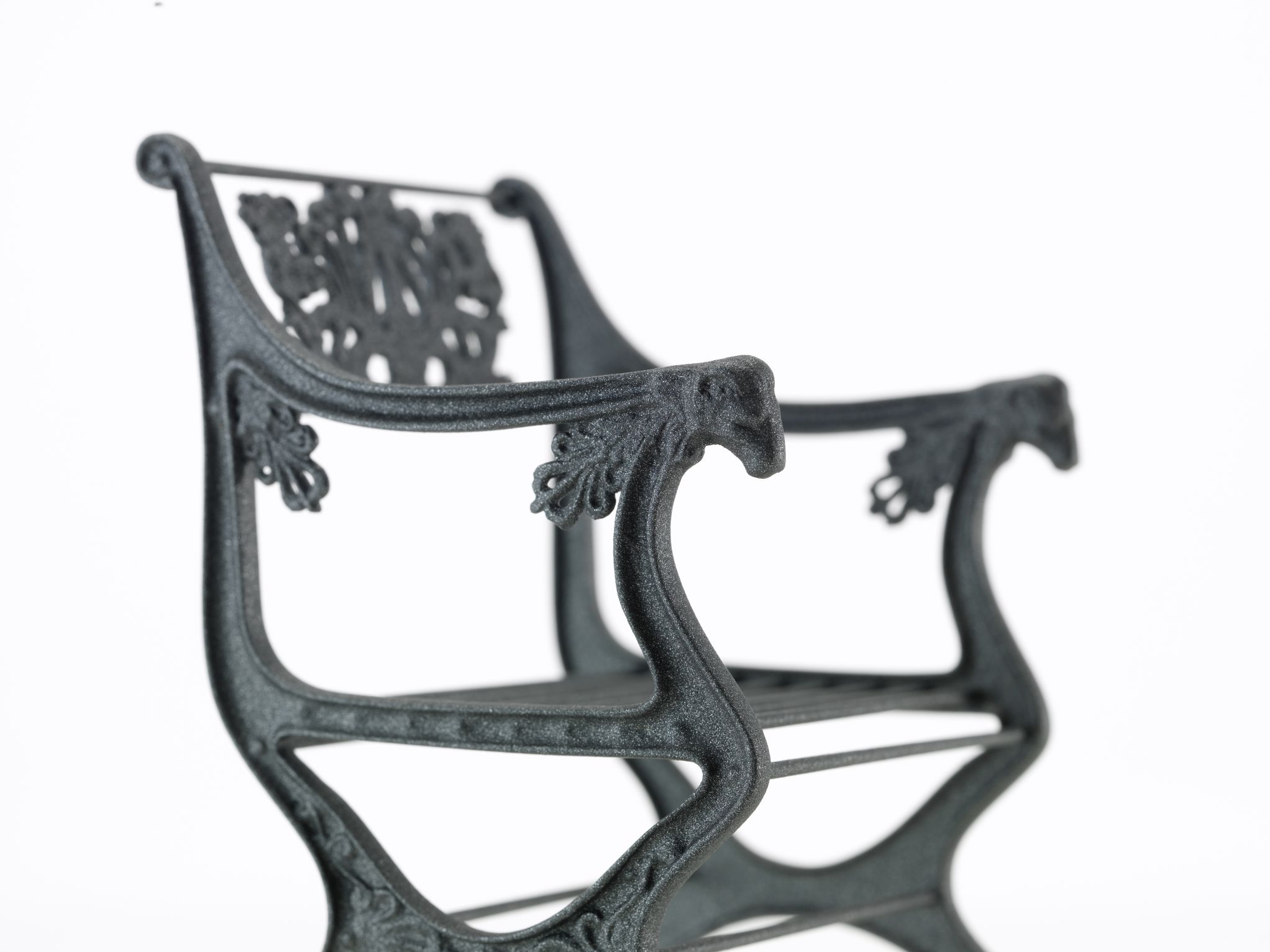 Detailaufnahme des Gartenstuhl [1820] Miniatur Vitra, ein dekorativer Miniaturstuhl mit filigranen Verzierungen.