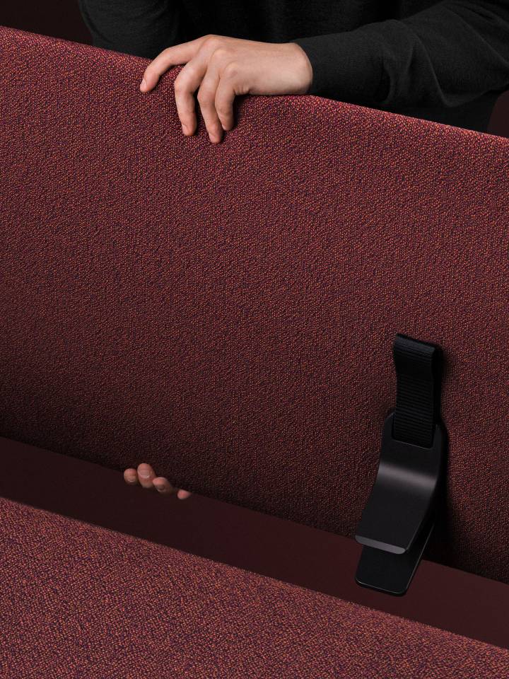 Detailaufnahme des roten Vitra Anagram Panels (110 cm) mit schwarzer Halterung und Händen.