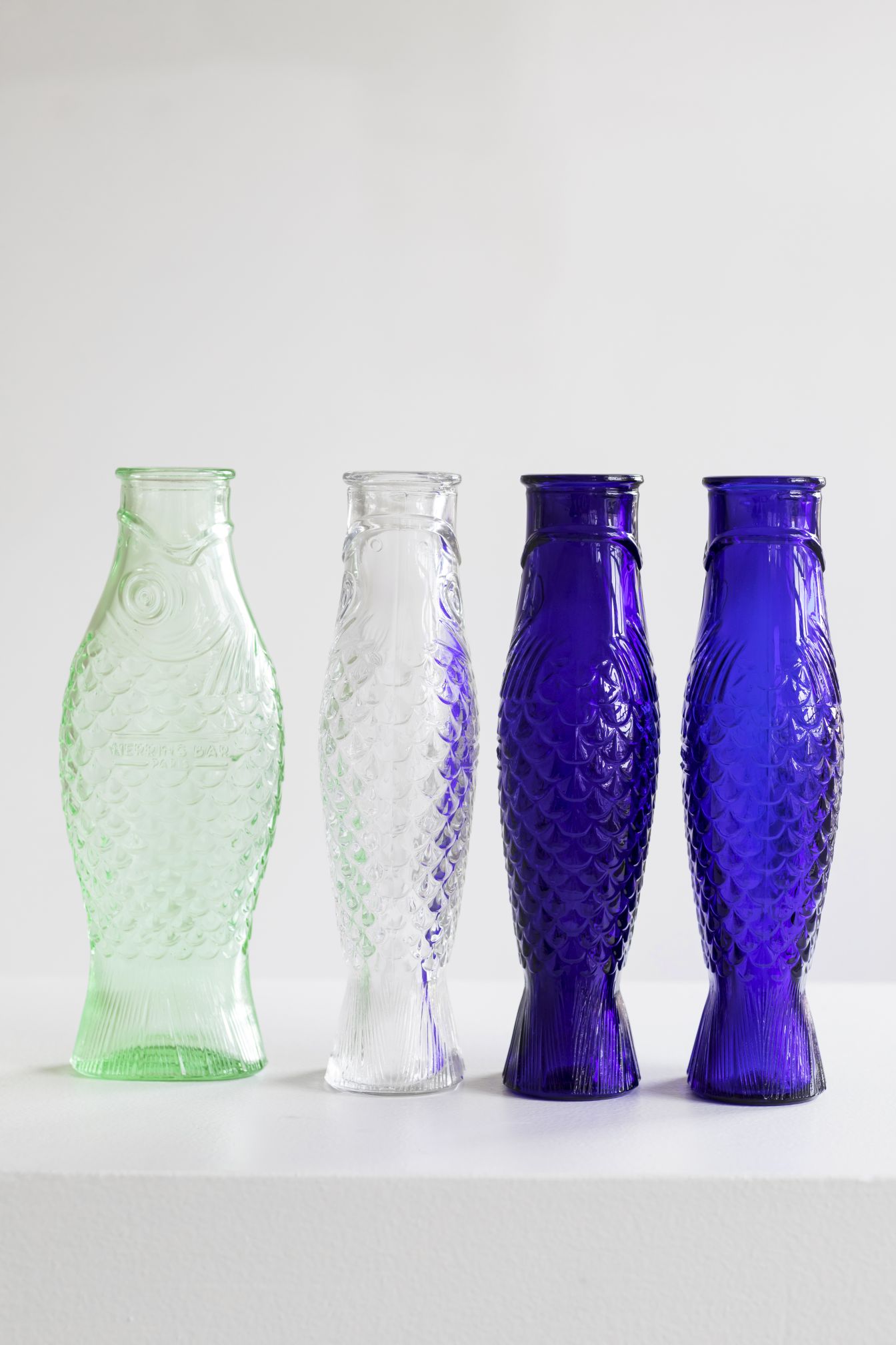 Vier dekorative Fischflaschen von Serax in Grün, Klar und Blau, Glasflaschen im Fischdesign.