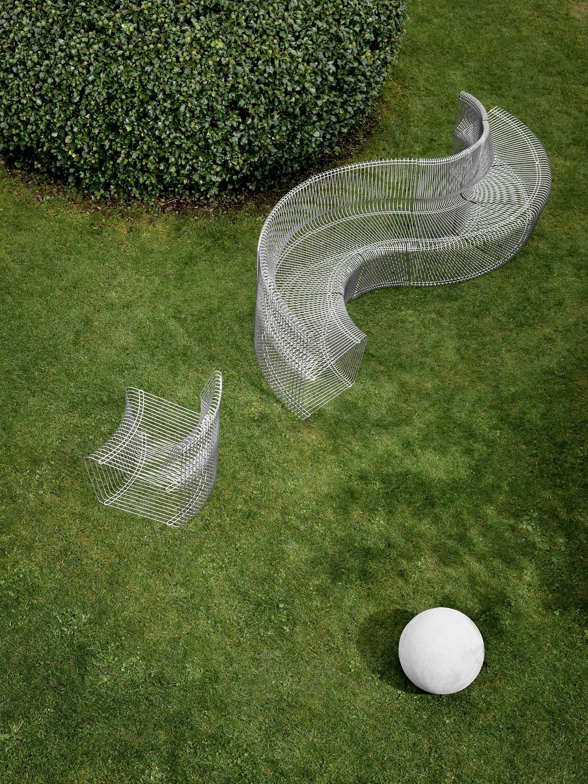 Pantonova System Sitzmodul: Geschwungene Draht Sitzbank und Stuhl von Montana auf Rasen, modernes Gartenmöbel Design.