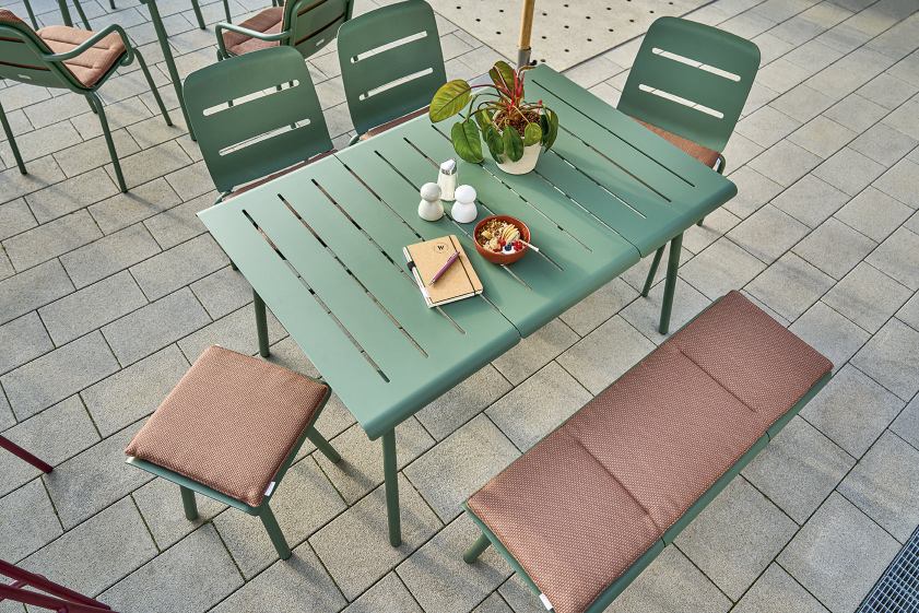 Weishäupl Vapio Stool Hocker und Gartentisch-Set in Grün mit braunen Sitzkissen auf einer Terrasse.