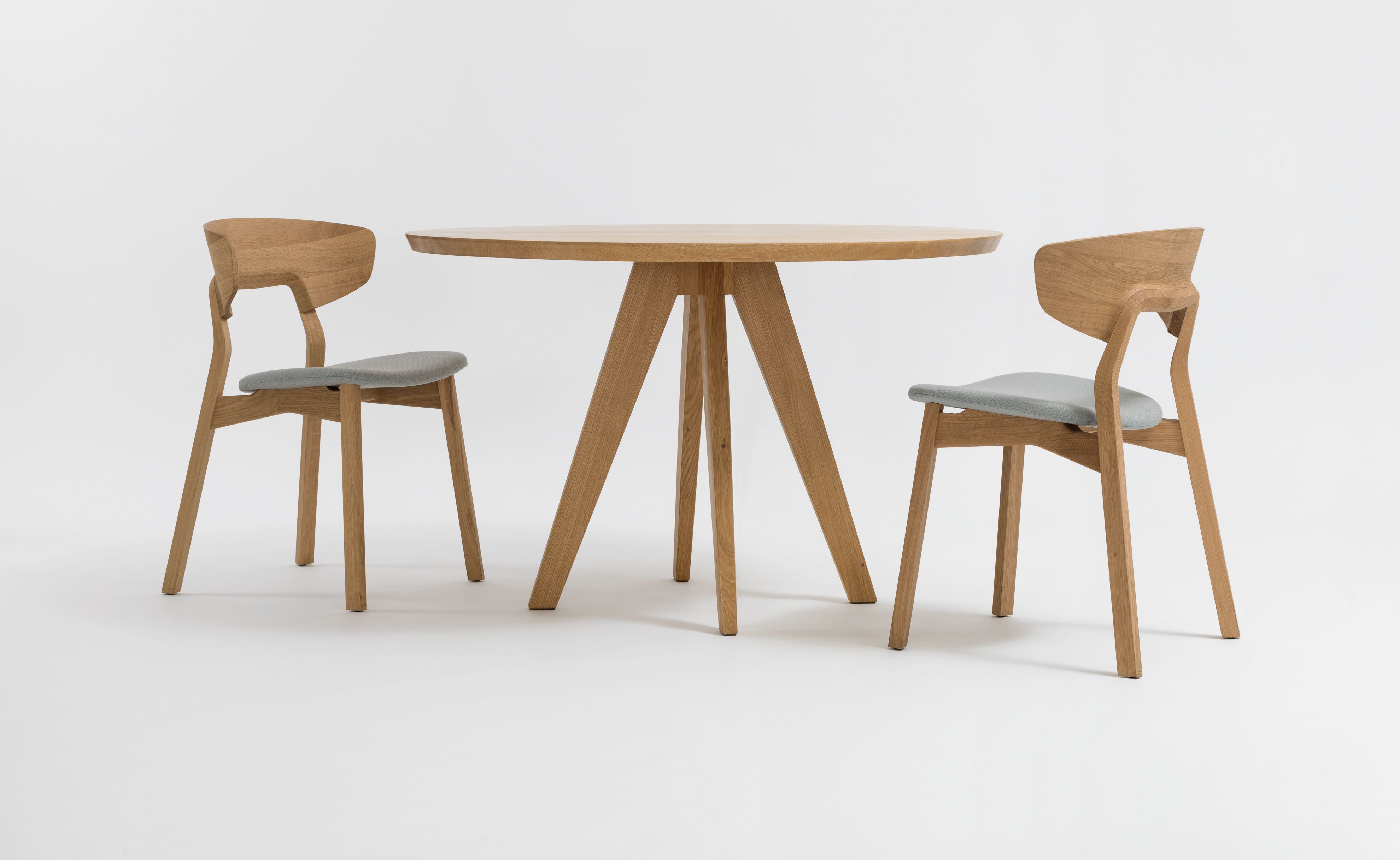 CENA Tisch, runder Esstisch aus Holz mit zwei Stühlen auf weißem Hintergrund.