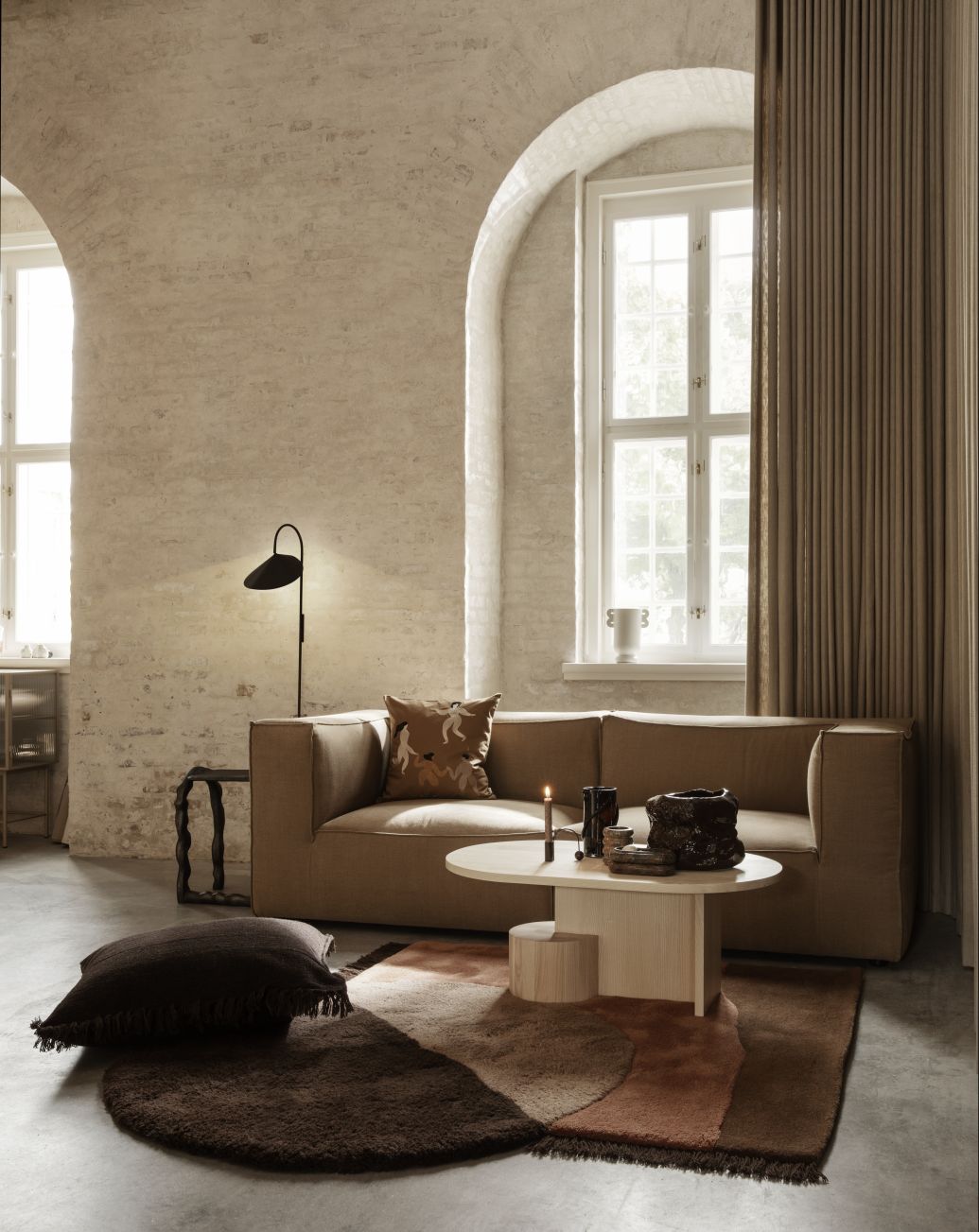 Wohnzimmer mit Ferm Living Couchtisch Insert, Sofa, Teppich und Dekoration in warmen Erdtönen.