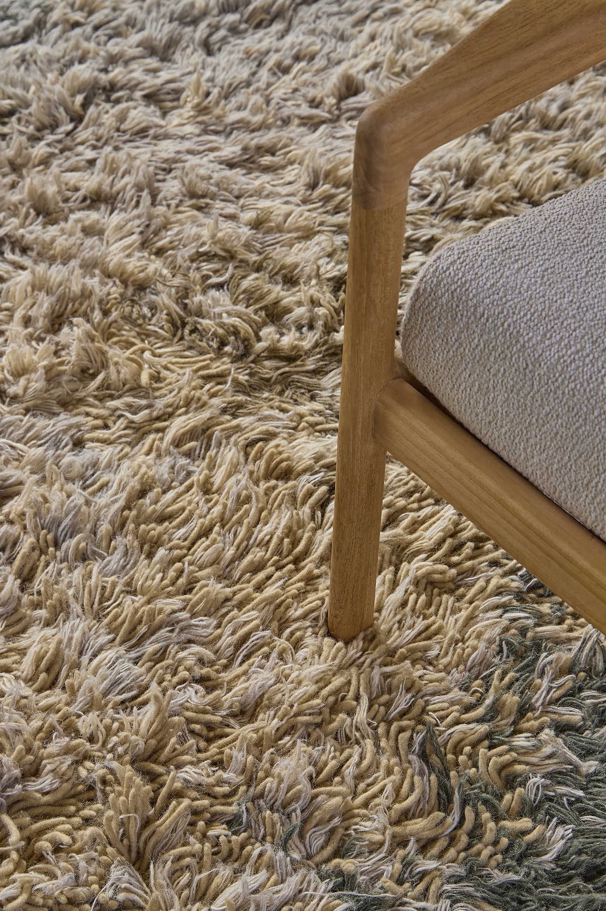 Detailansicht des Alga Rug Teppichs von Nanimarquina mit beiger Textur und Stuhlbein.