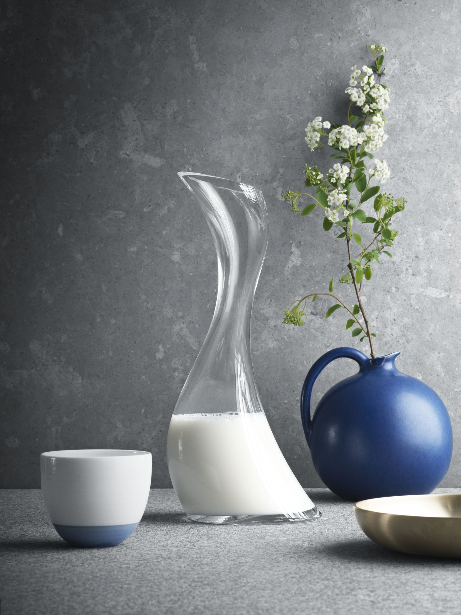 Elegante Cobra Karaffe aus Klarglas von Georg Jensen, gefüllt mit Milch, neben Tasse und Vase.