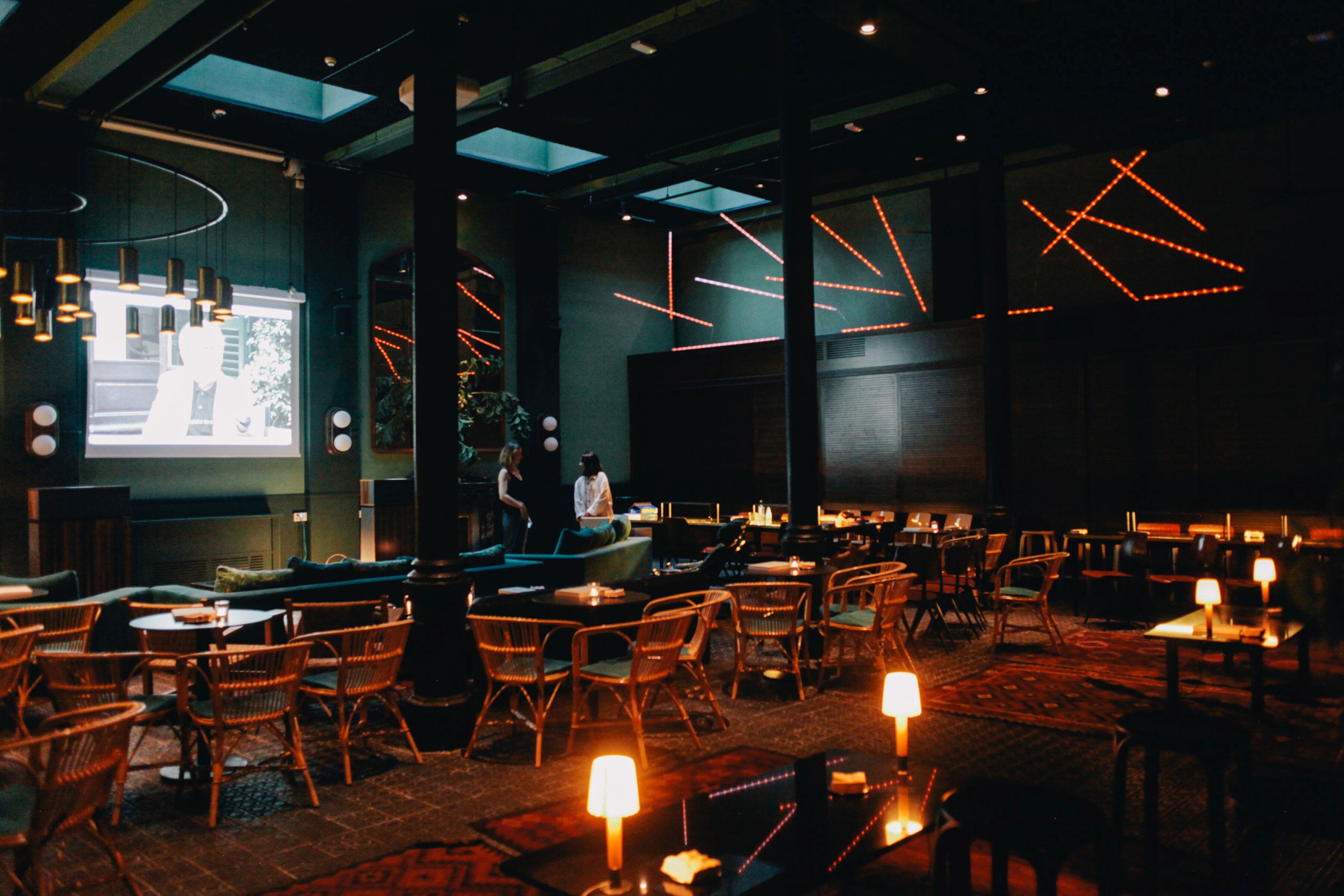 Innenaufnahme eines Restaurants mit La Colilla Pendelleuchte von Santa & Cole, die über Sitzbereichen hängt.