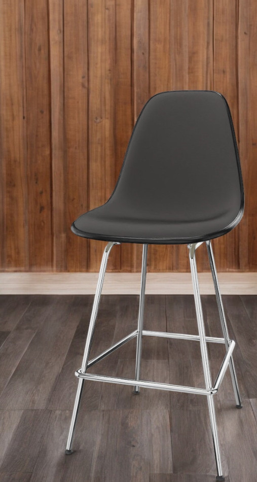 Schwarzer Eames Plastic Bar Stool Barhocker mit verchromtem Gestell und Vollpolsterung vor Holzwand.