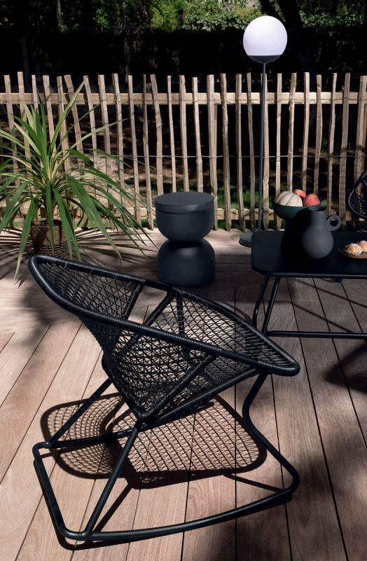 Schwarzer Sixties Outdoor Sessel von Fermob mit Flechtmuster auf Holzterrasse. Gartenmöbel für entspannte Stunden.