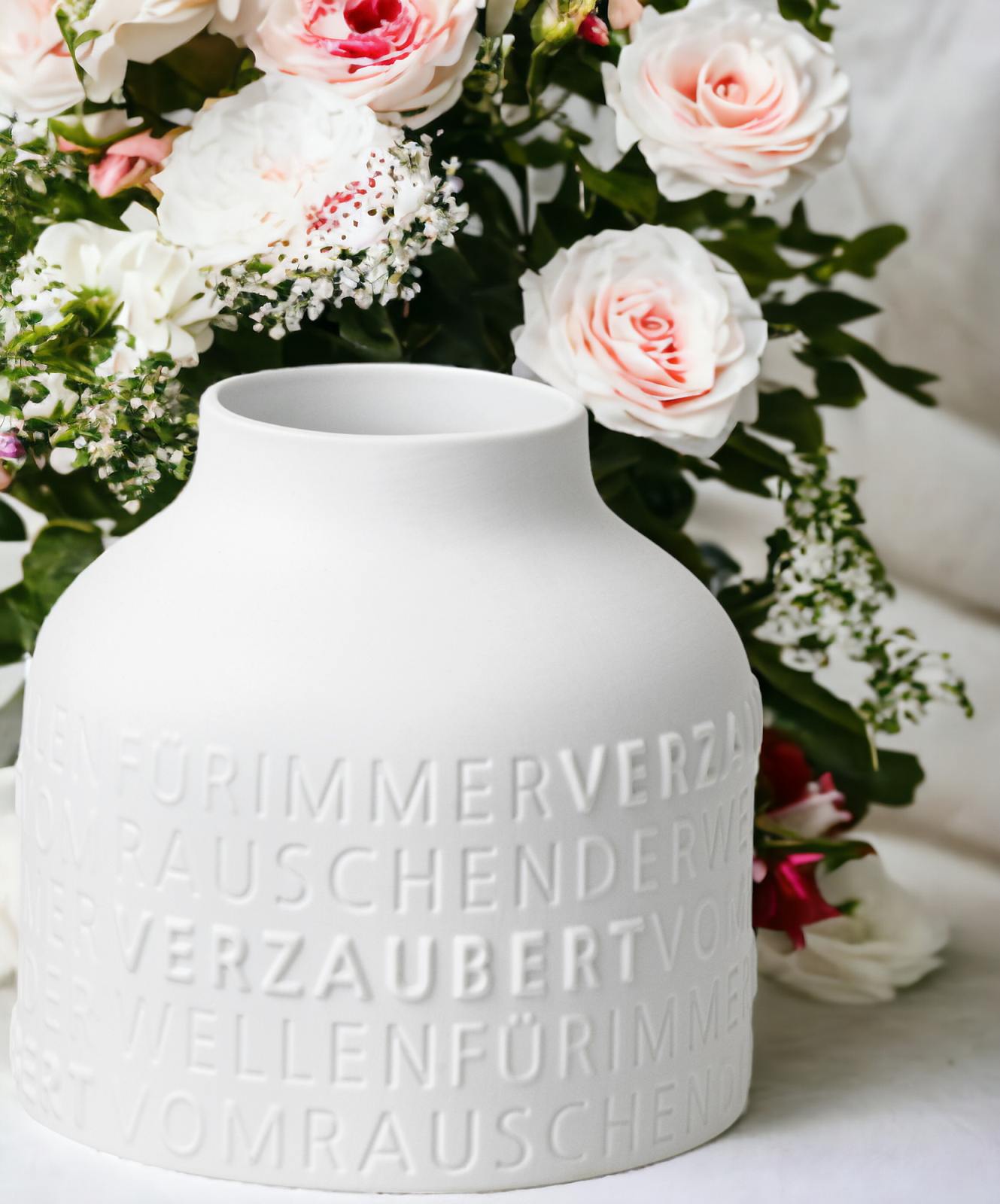 Nahaufnahme der weißen Räder Vase Für immer verzaubert mit zarten Rosen und Schleierkraut im Hintergrund.