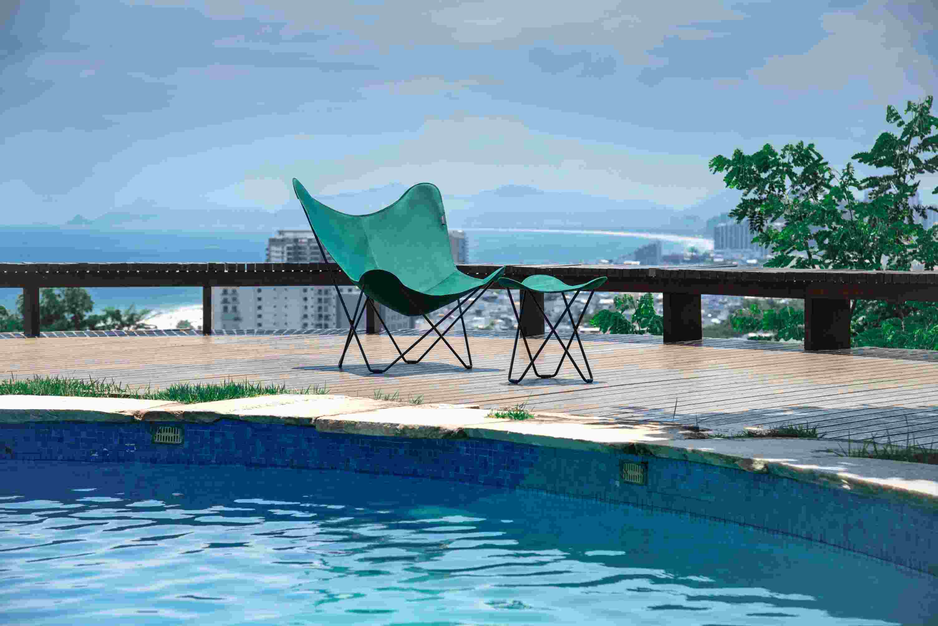 Mariposa Outdoor Butterfly Chair in Waldgrün neben einem Pool auf einer Holzterrasse.