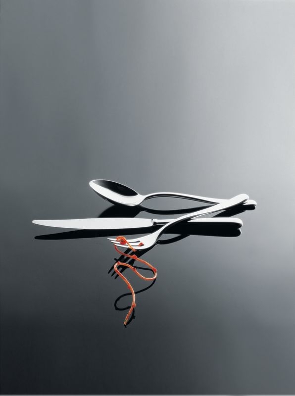 Alessi Caccia Besteck: Messer, Gabel und Löffel aus Edelstahl auf glänzendem Untergrund. Hochwertiges Besteckset für stilvolles Essen.