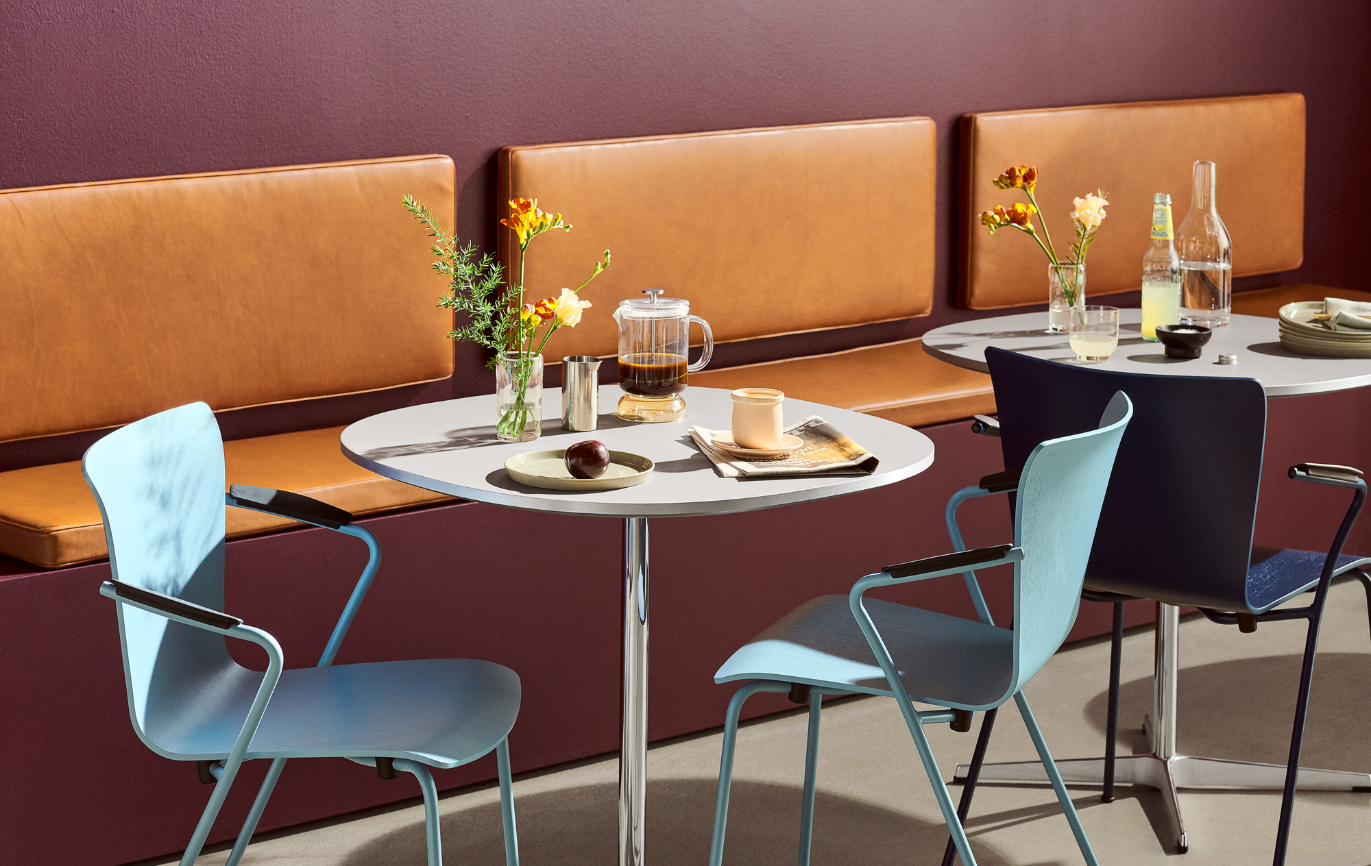 Helle Vico Stühle von Fritz Hansen umgeben Tische in einem modernen Café-Ambiente.