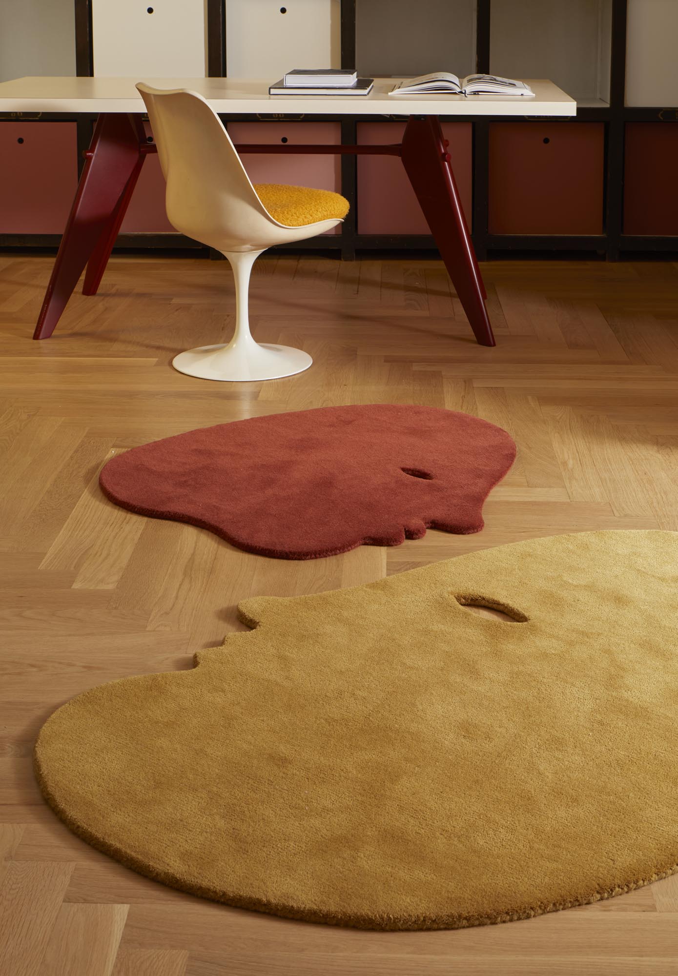 Detailaufnahme von zwei Nanimarquina Talk Talk Teppichen in Rot und Gelb auf einem Holzboden.