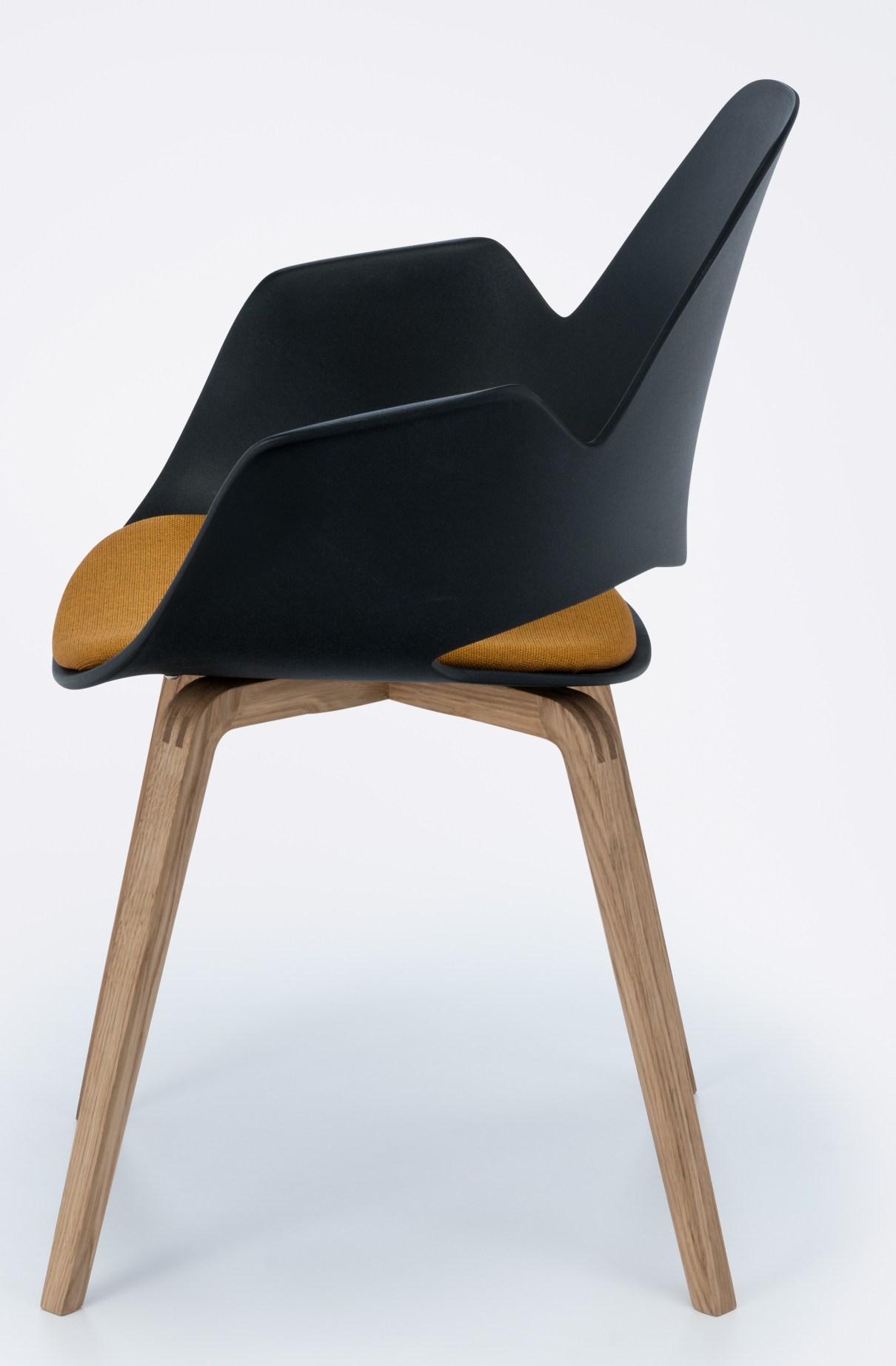 Falk Stuhl mit Armlehne von Houe, schwarze Sitzschale, Eiche Beine und gelbes Kissen.
