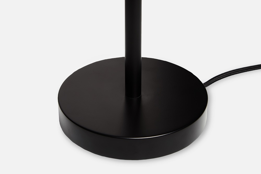 Detailaufnahme: Schwarzer, runder Lampenfuß der Cono Tischleuchte von Woud mit Textilkabel.