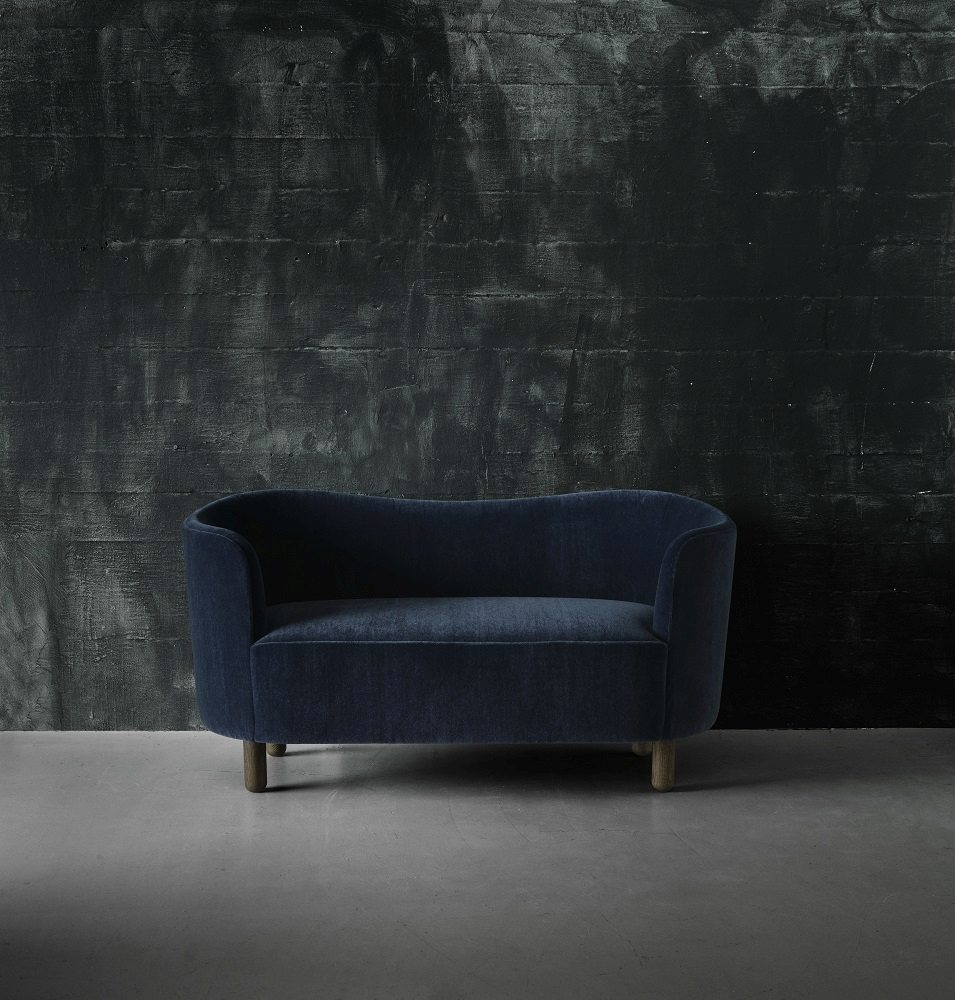 Blaues Mingle Sofa von Audo, ein Zweisitzer-Sofa mit dunklem Hintergrund und Holzfüßen.