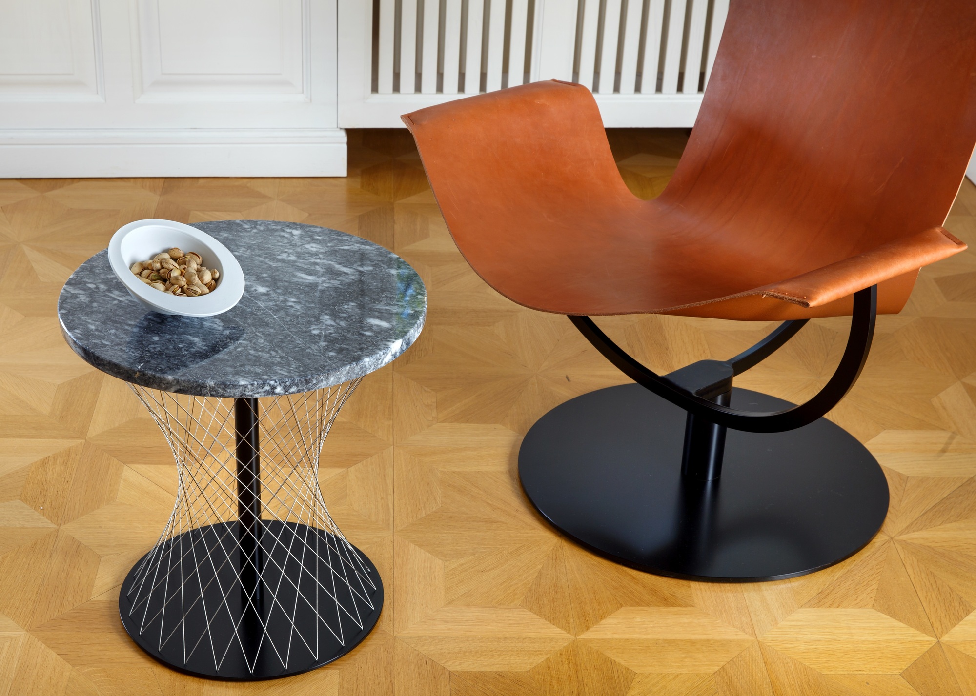 Weiße Pivot Schale (16cm) auf Marmortisch mit Pistazien, neben einem braunen Ledersessel. Dekorative Schale für Snacks.