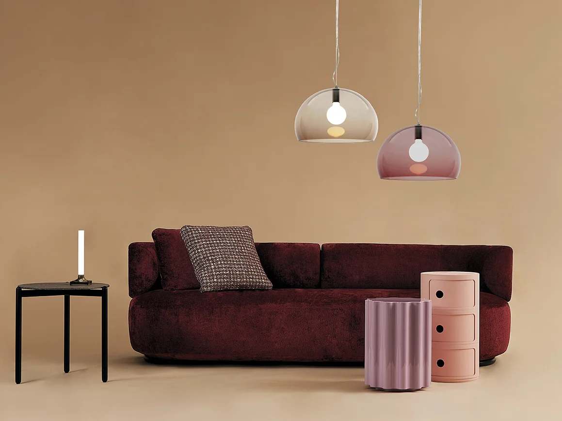 Zwei Kartell Fl/Y Pendelleuchten in Braun und Rosa über einem roten Sofa.