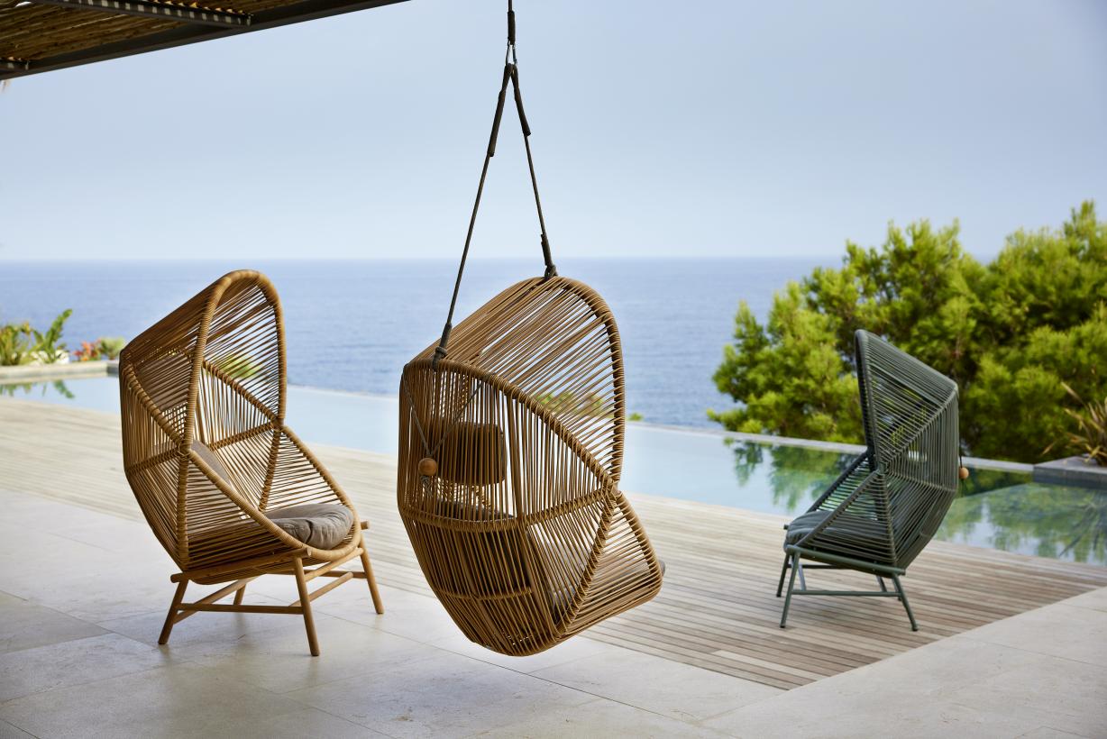 Drei Cane-Line Hive Sessel: Ein Hängesessel und zwei stehende Outdoor Sessel aus Rattan.
