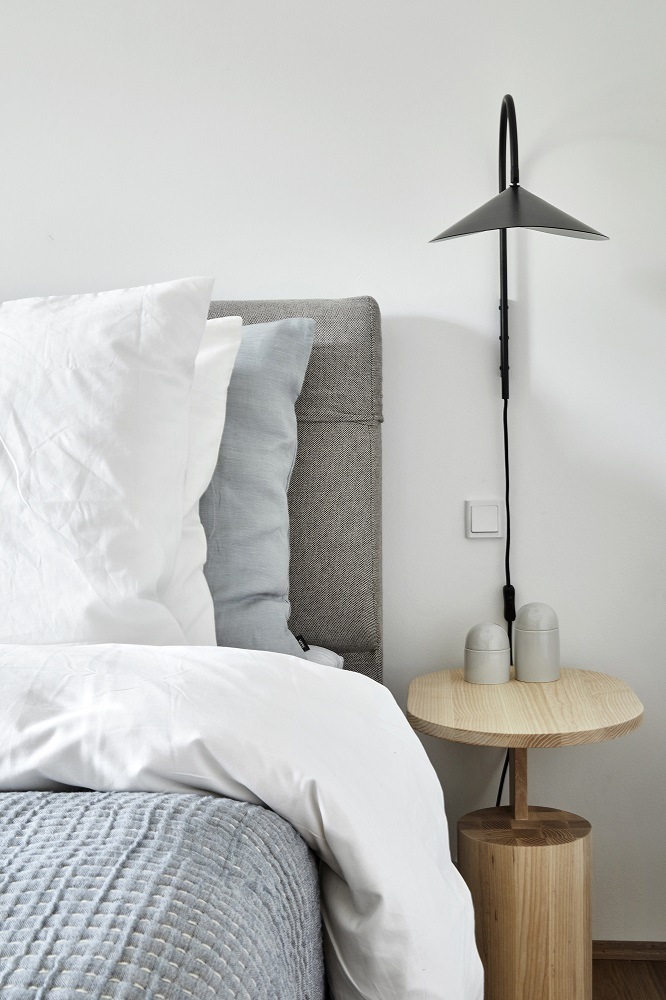 Schlafzimmer-Szene mit Arum Wandleuchte von Ferm Living in Schwarz über Nachttisch. Moderne Wandlampe.