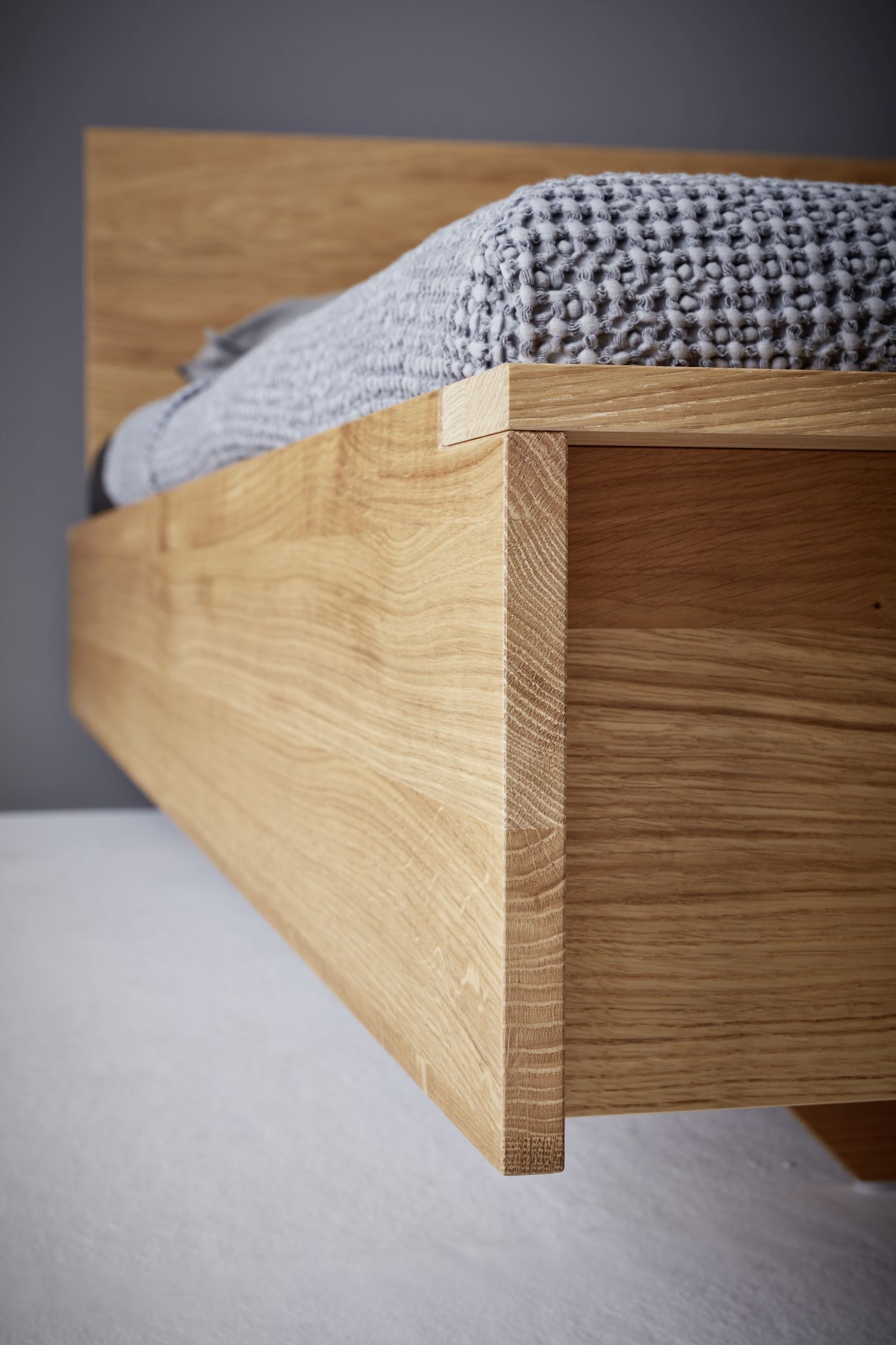 Detailaufnahme vom Flai Bett (Eiche) von Müller Möbelwerkstätten mit grauer Tagesdecke.