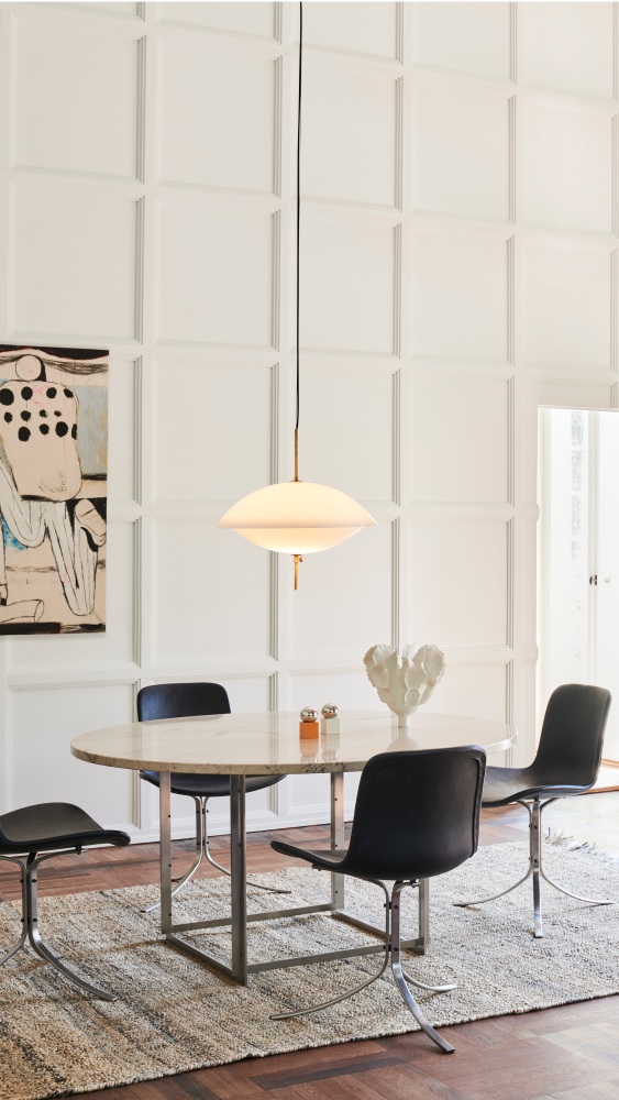 Helle Clam Pendelleuchte von Fritz Hansen über Esstisch mit Stühlen und Teppich.