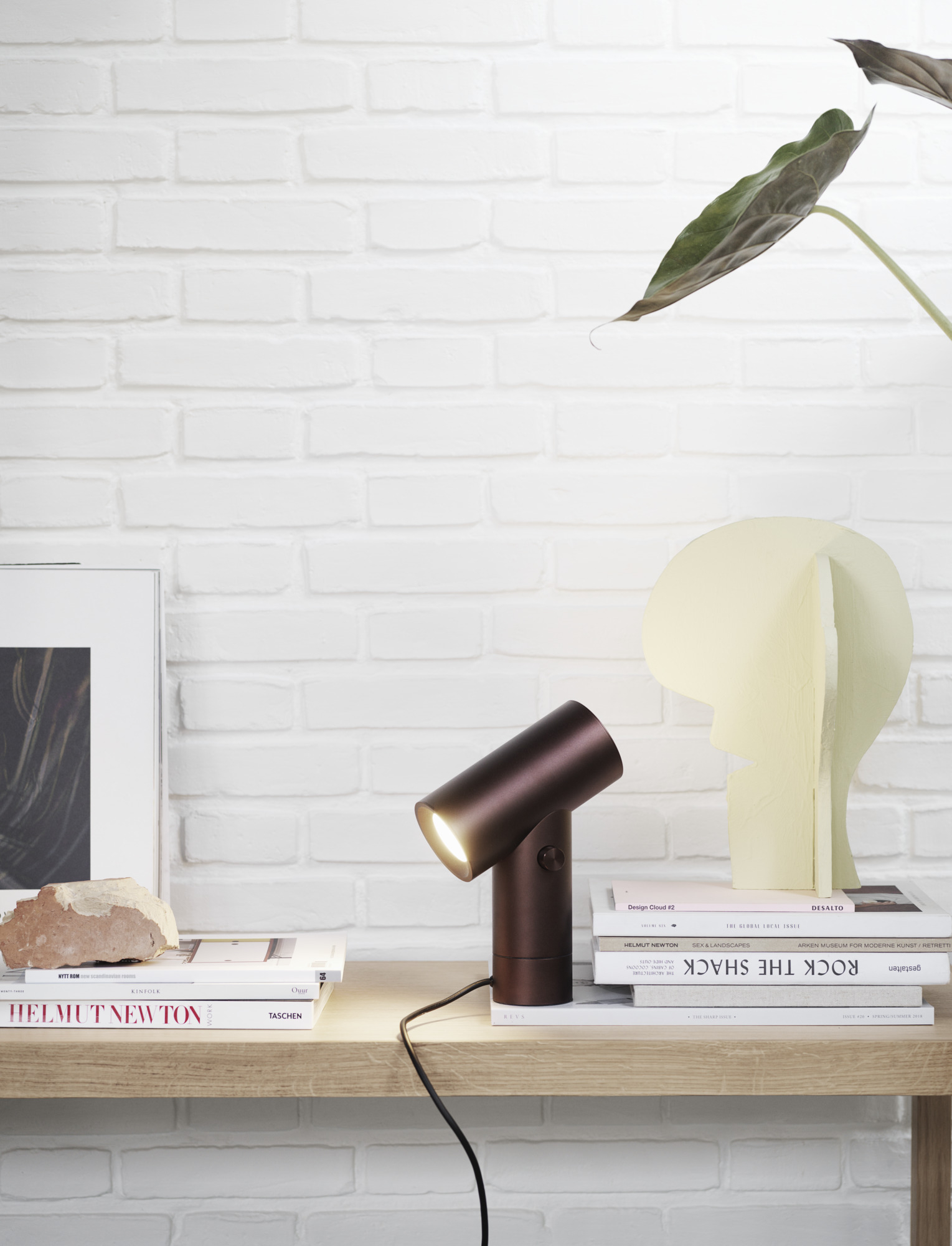 Schwarze Beam Lamp Tischleuchte von Muuto auf einem Tisch mit Büchern und Dekoration.