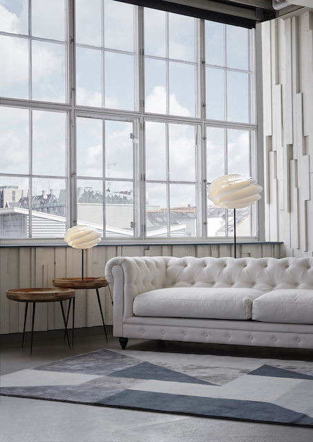 Swirl Stehleuchte von Le Klint im Wohnzimmer mit Sofa und Teppich.