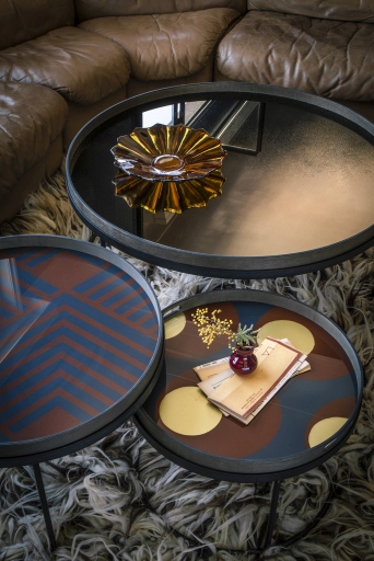 Nahaufnahme von drei Ethnicraft Beistelltischen mit verschiedenen Mustern und einer bronzefarbenen Schale.