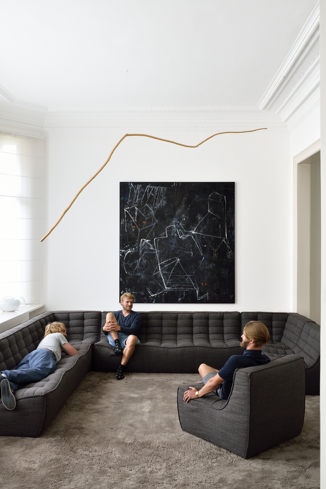 N701 Sofa von Ethnicraft: Graues 3-Sitzer Modulsofa mit Personen im modernen Wohnzimmer.