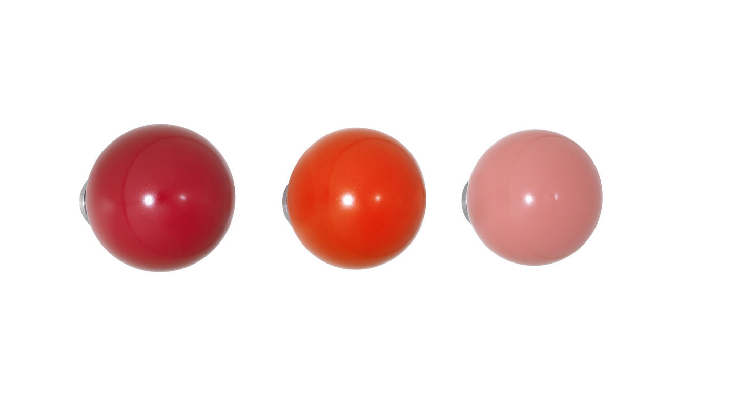 Vitra Coat Dots Garderobenhaken 3er-Set in Rot, Orange und Rosa auf weißem Hintergrund.