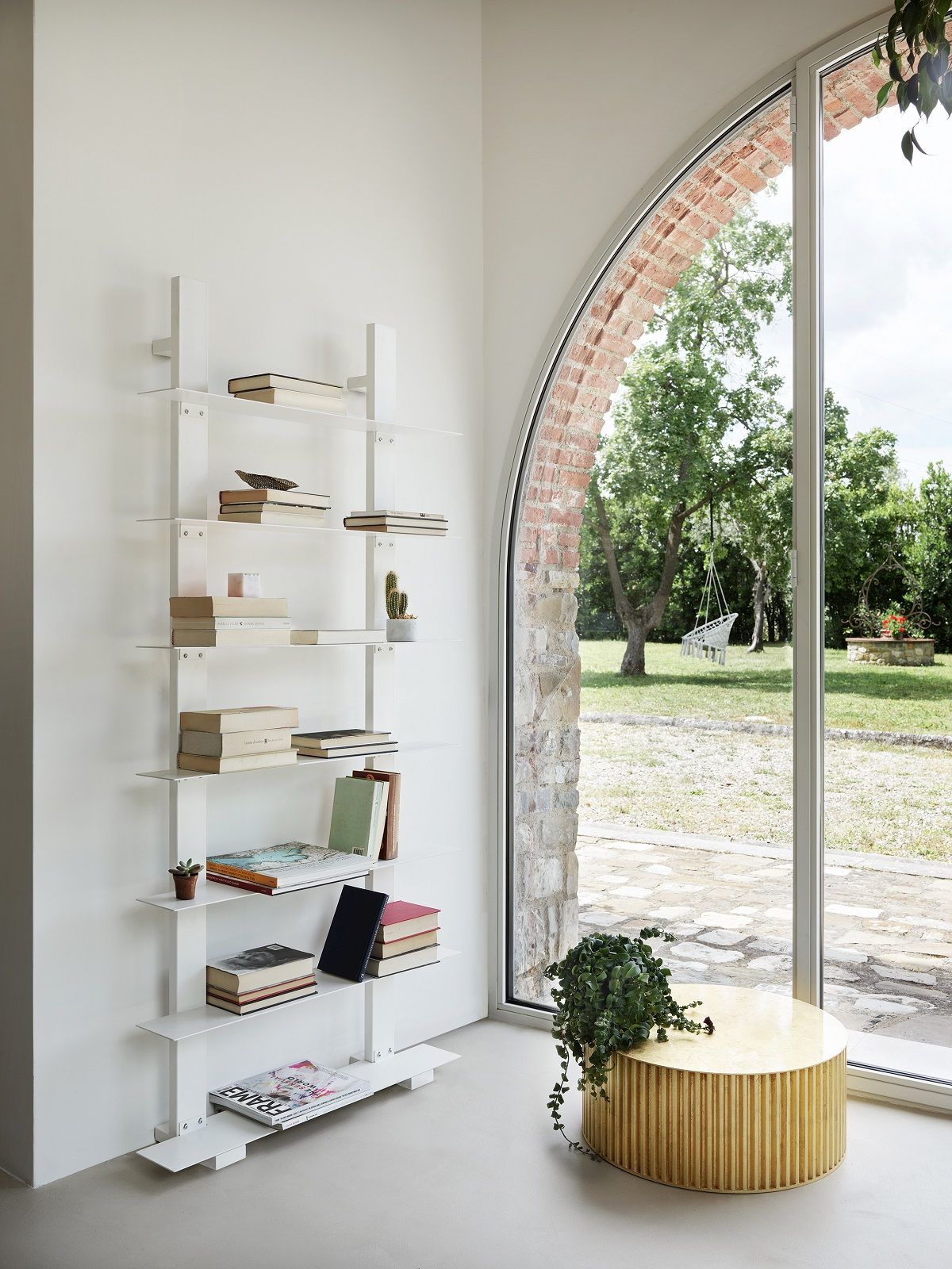 Goldener Herclino Couchtisch von Opinion Ciatti im modernen Wohnzimmer mit Bücherregal und Fenster.